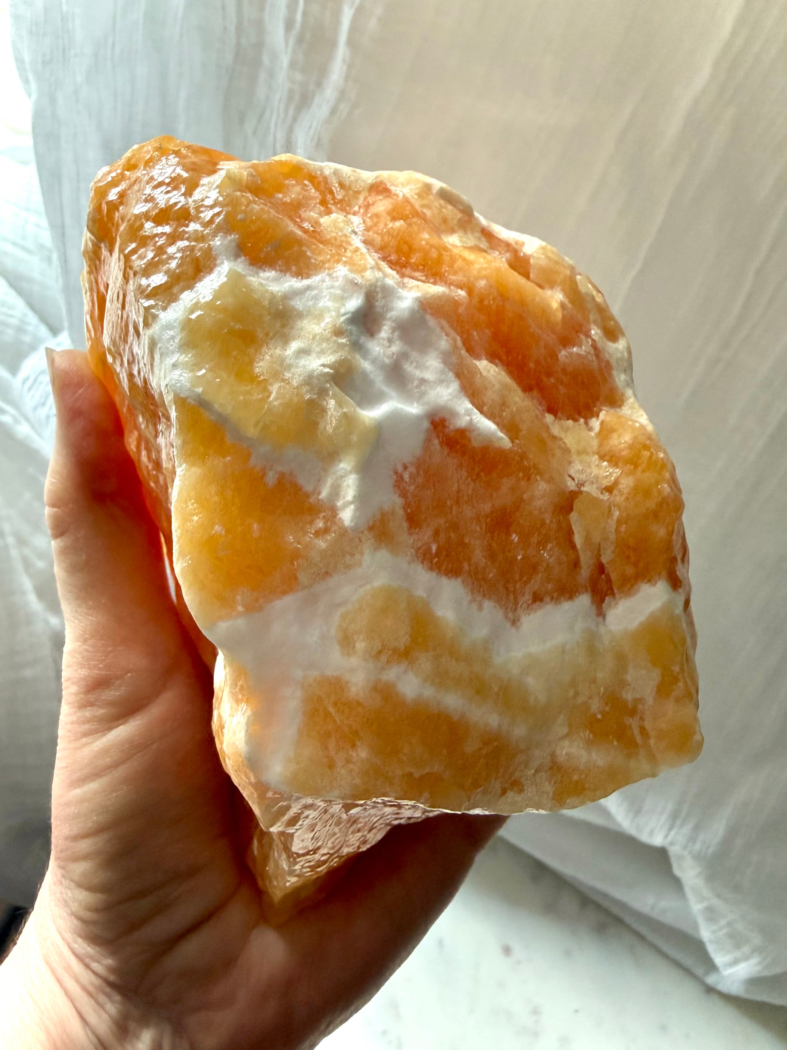Handheld Orange Calcite statement crystal with creamy white calcite matrix and rich honey-orange color