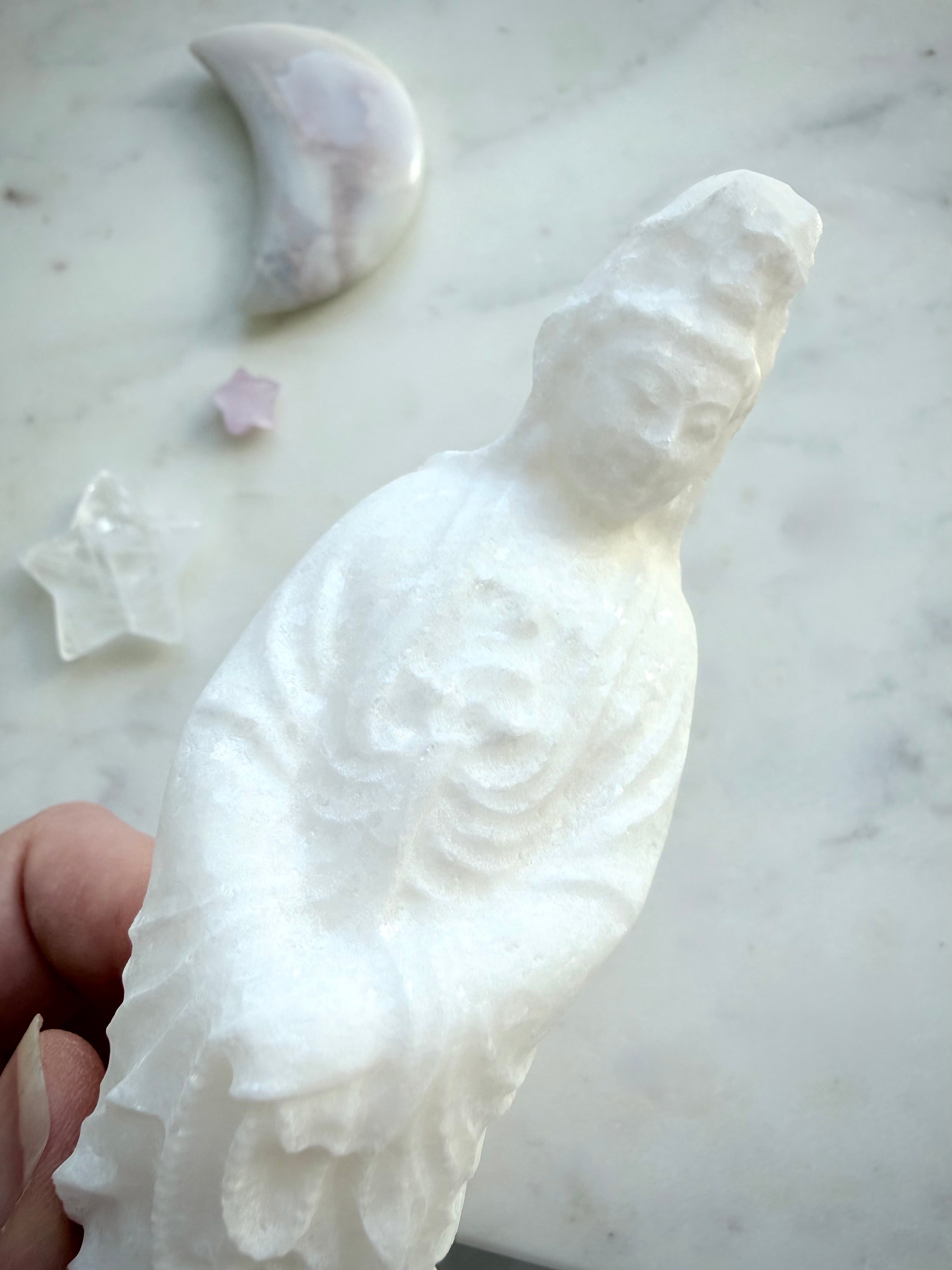 Close-up of White Jade Quan Yin statue showing serene facial features and natural crystalline texture