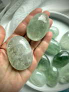 Two polished Prasiolite palm stones held in hand showing natural crystal formations