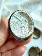 Pyrite worry stone close-up with brilliant reflective luster, crystalline texture and mineral inclusions