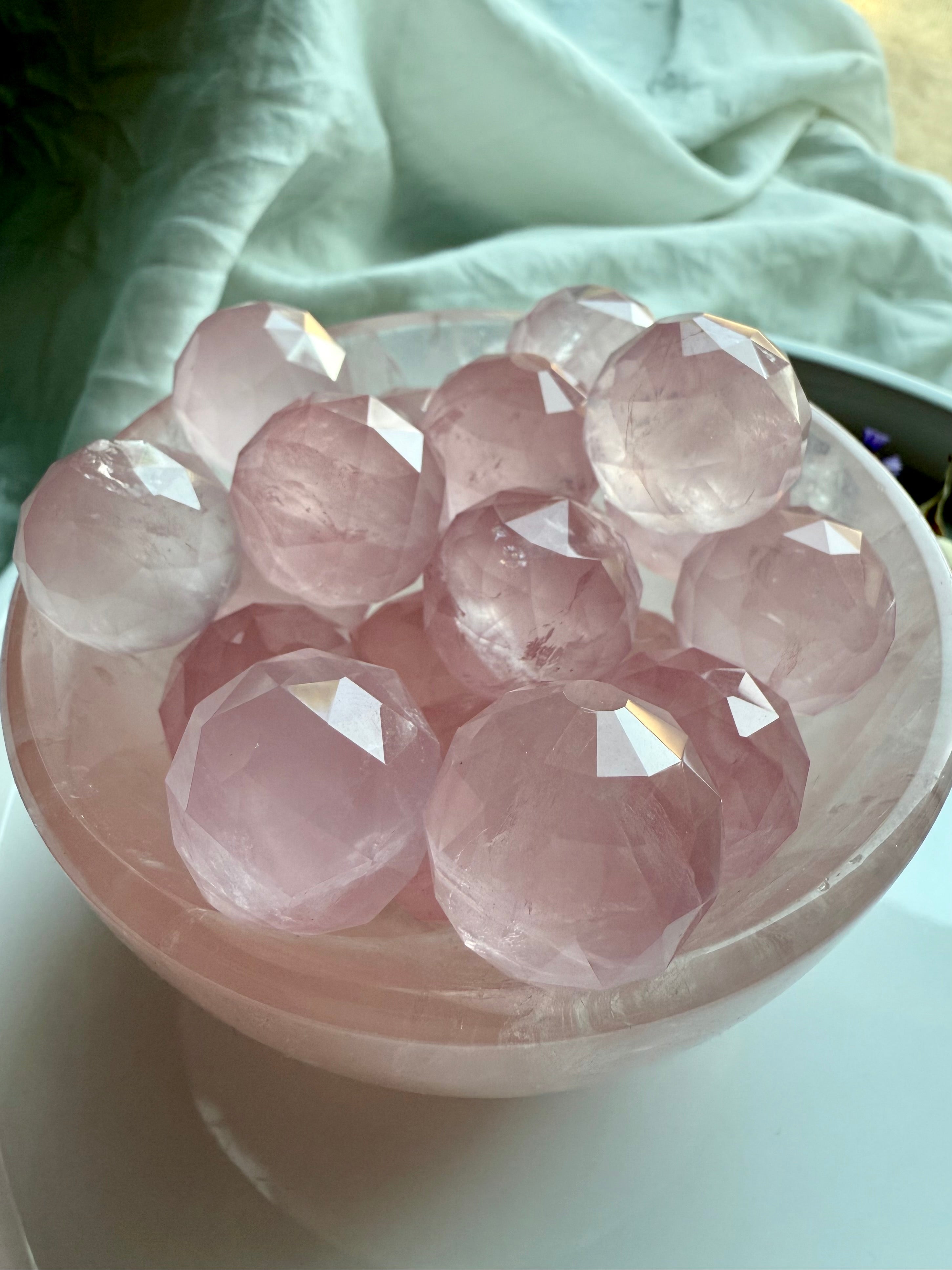 Pink rose quartz crystal balls in a crystal bowl for heart chakra healing