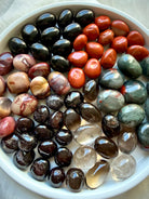 Root Chakra healing stones arranged in a white bowl with Bloodstone, Black Obsidian, Red Jasper, Smoky Quartz, and Garnet