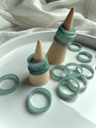 Natural Blue Water Jade rings stacked on wooden ring cones, showcasing flat jadeite bands in calming aqua-green tones for heart chakra healing and crystal jewelry gifting