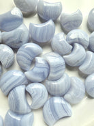 Close-up of polished Blue Lace Agate crescent moon carvings highlighting soft blue color and white lace banding