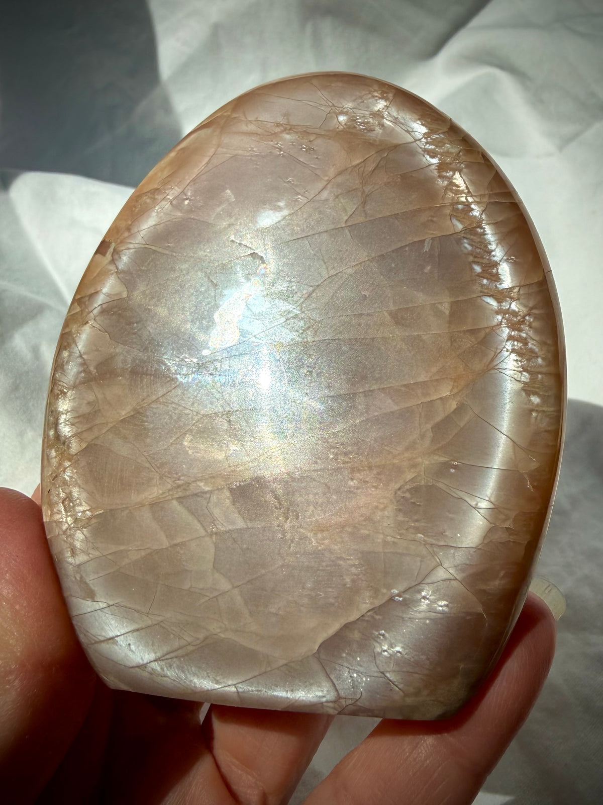 Peach Moonstone freeform held in hand with bright silvery Moonstone shimmer and subtle rainbow flash
