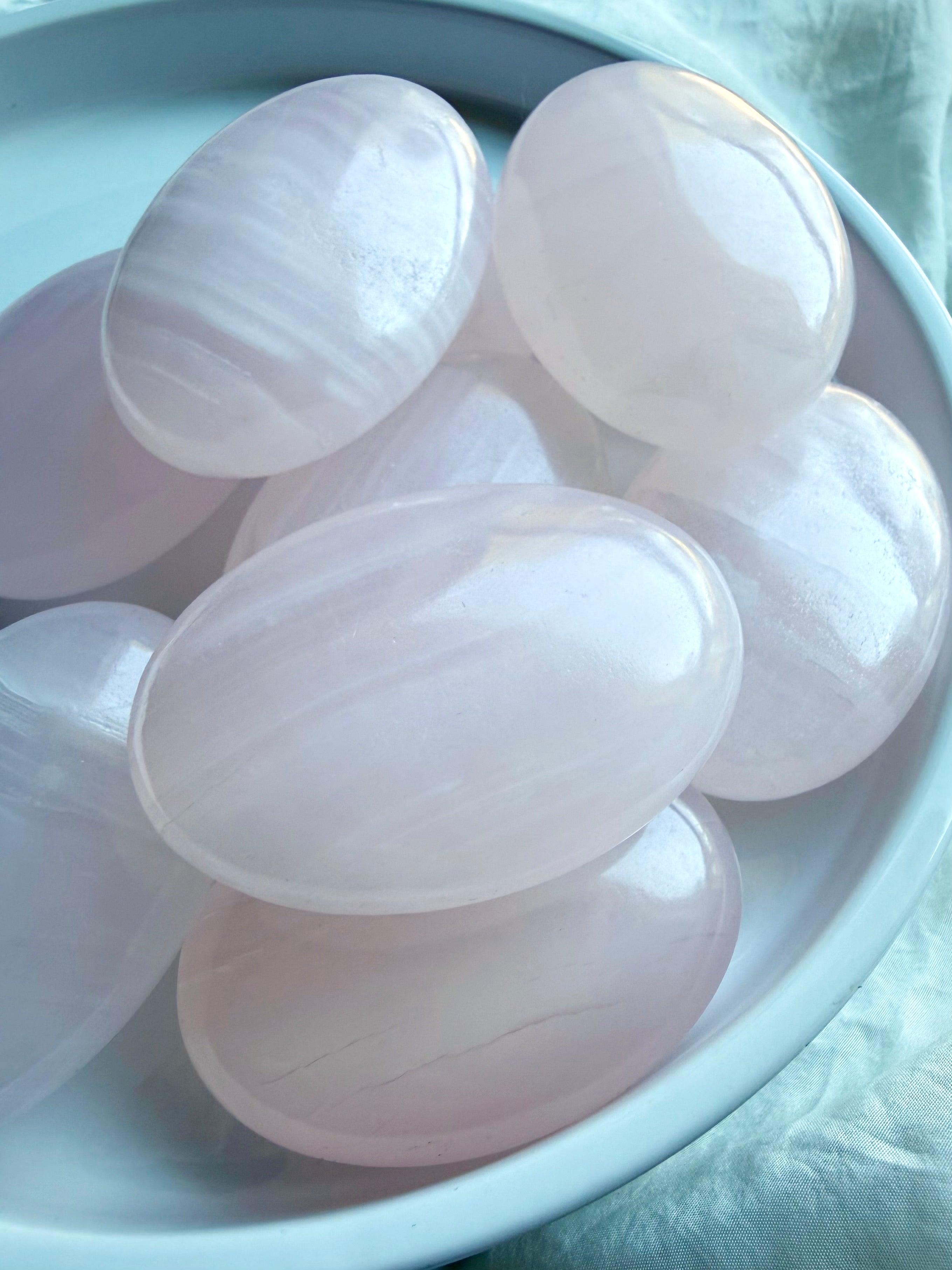 Assorted Pink Calcite palm stones with smooth polished surfaces and gentle pastel pink tones