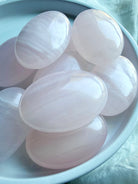 Assorted Pink Calcite palm stones with smooth polished surfaces and gentle pastel pink tones