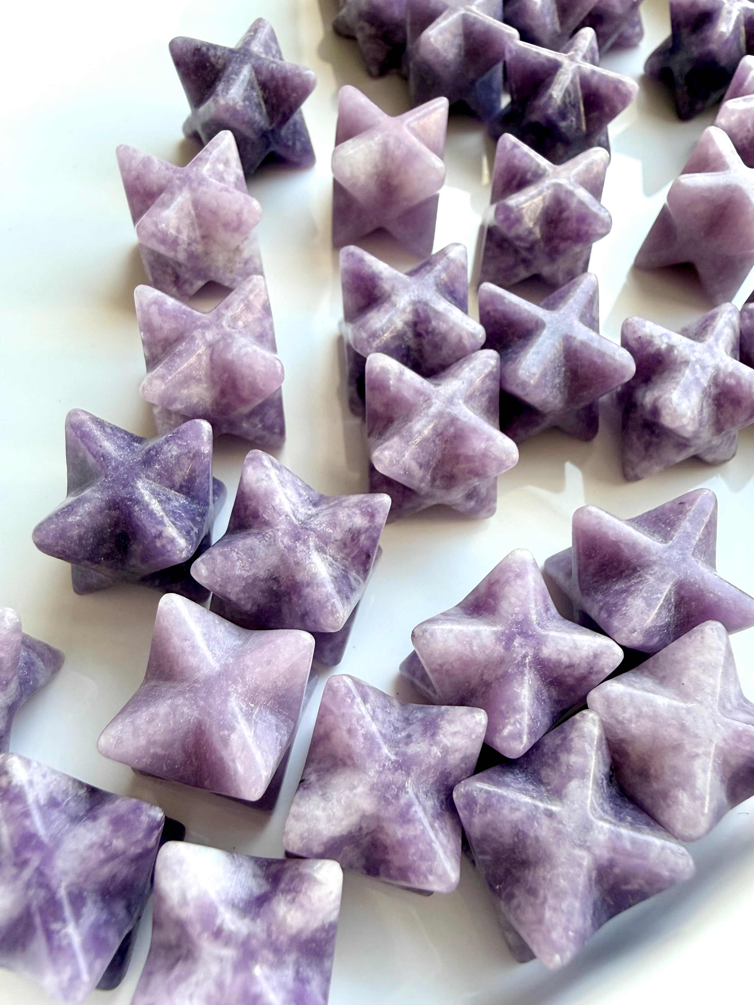 close-up mix of lepidolite merkaba stars showing natural variation in tone and pattern, calming crystals for nervous system support