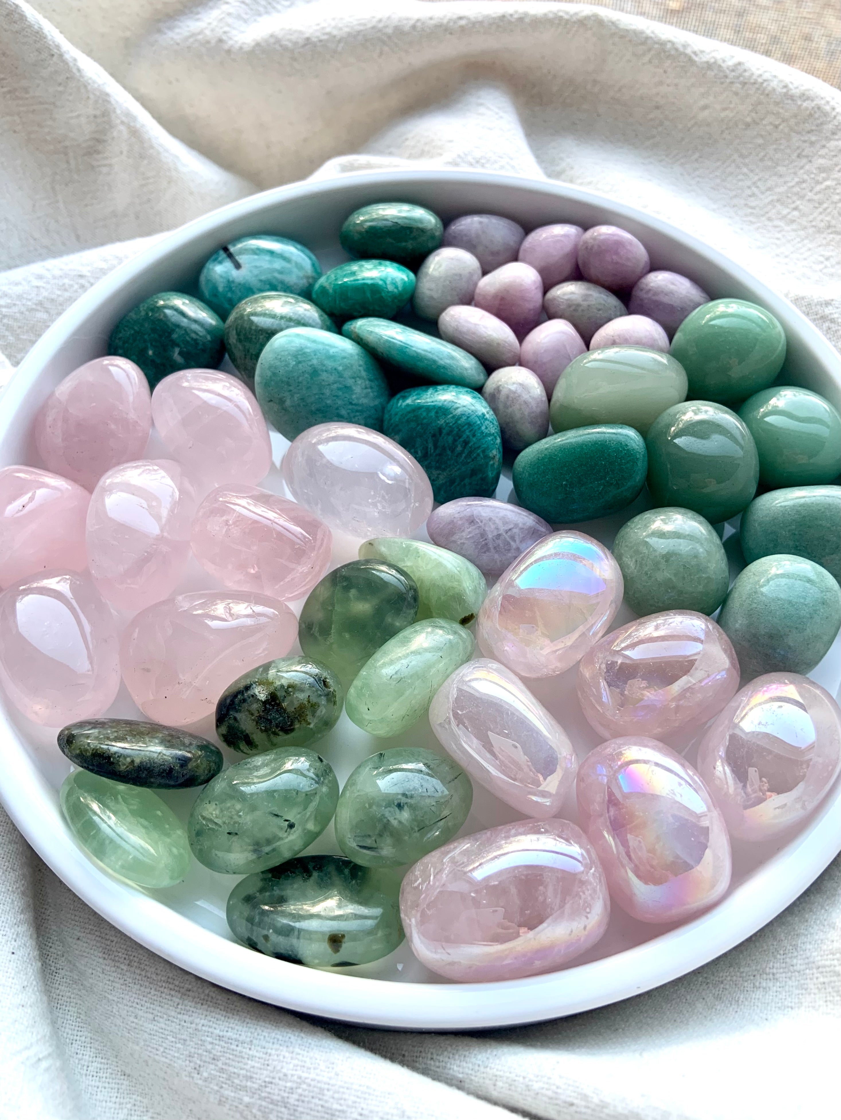 Wide-angle view of Heart Chakra crystal healing set with grouped pink and green tumbles arranged on a white plate to show color variety and quality.