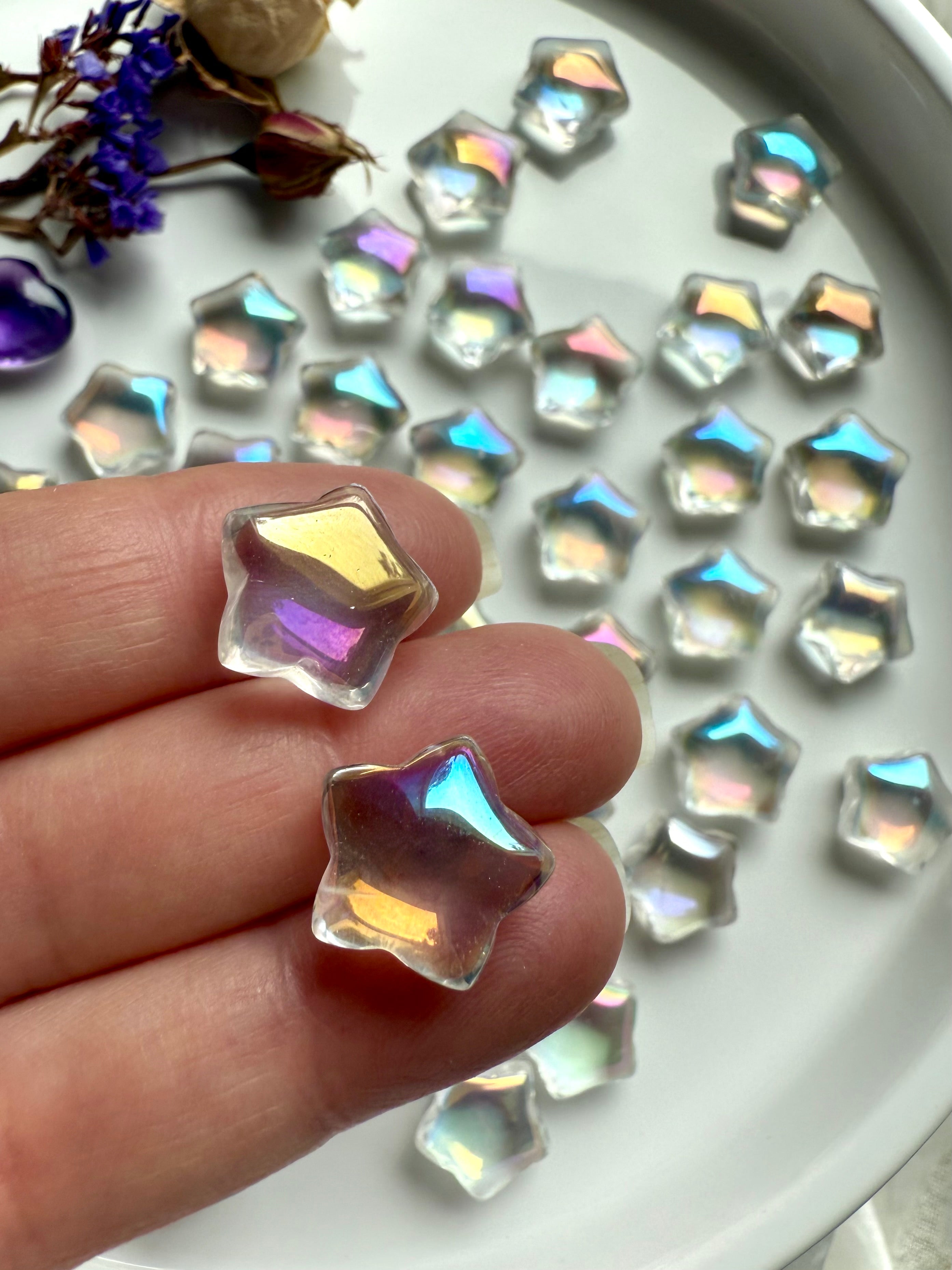 Close-up of mini aura quartz star carvings with opalescent rainbow light — pocket-sized crystals for healing, peace, and meditation