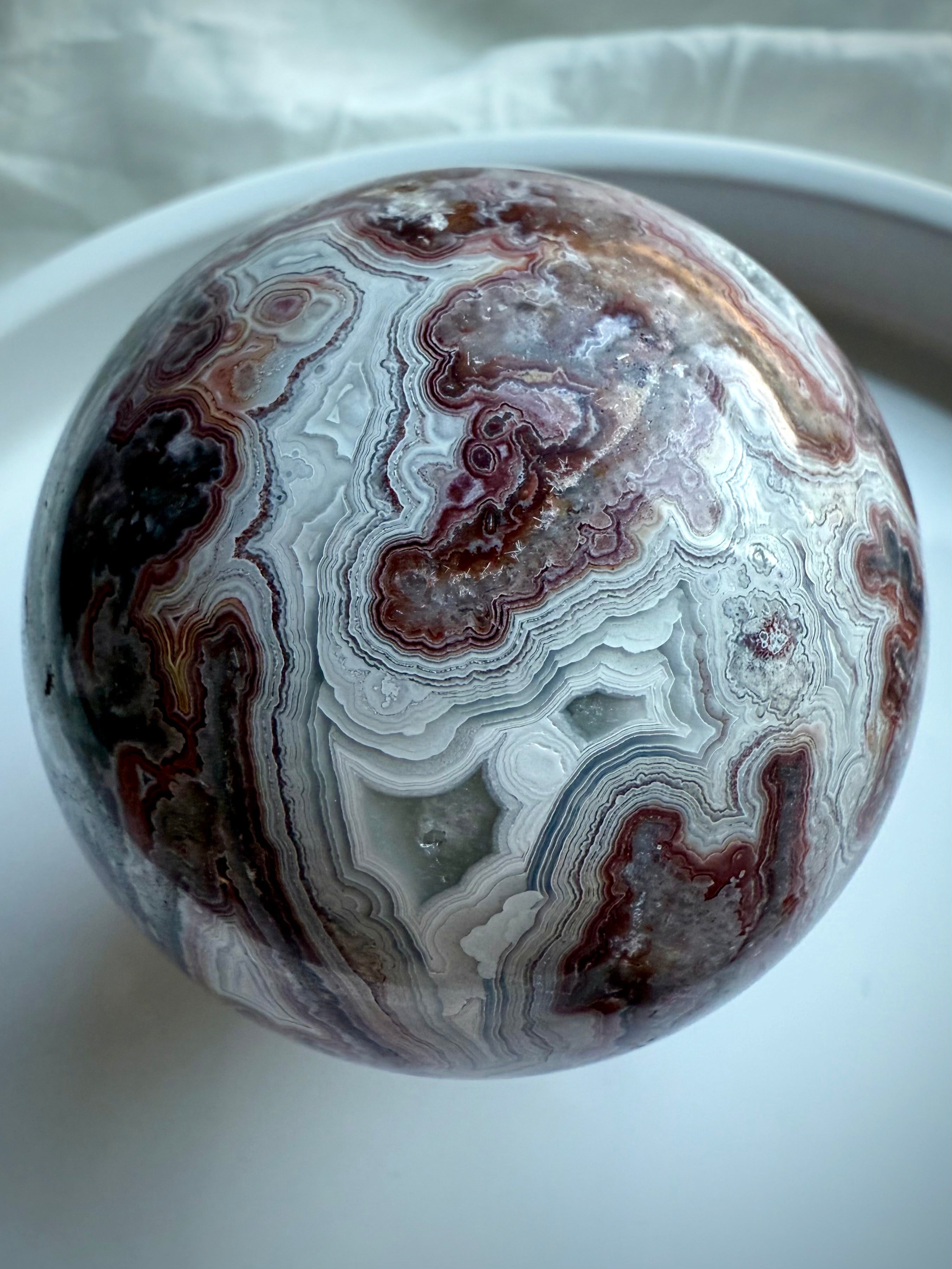 Crazy Lace Agate sphere with druzy window and complex red, white, and gray banding for energetic stability