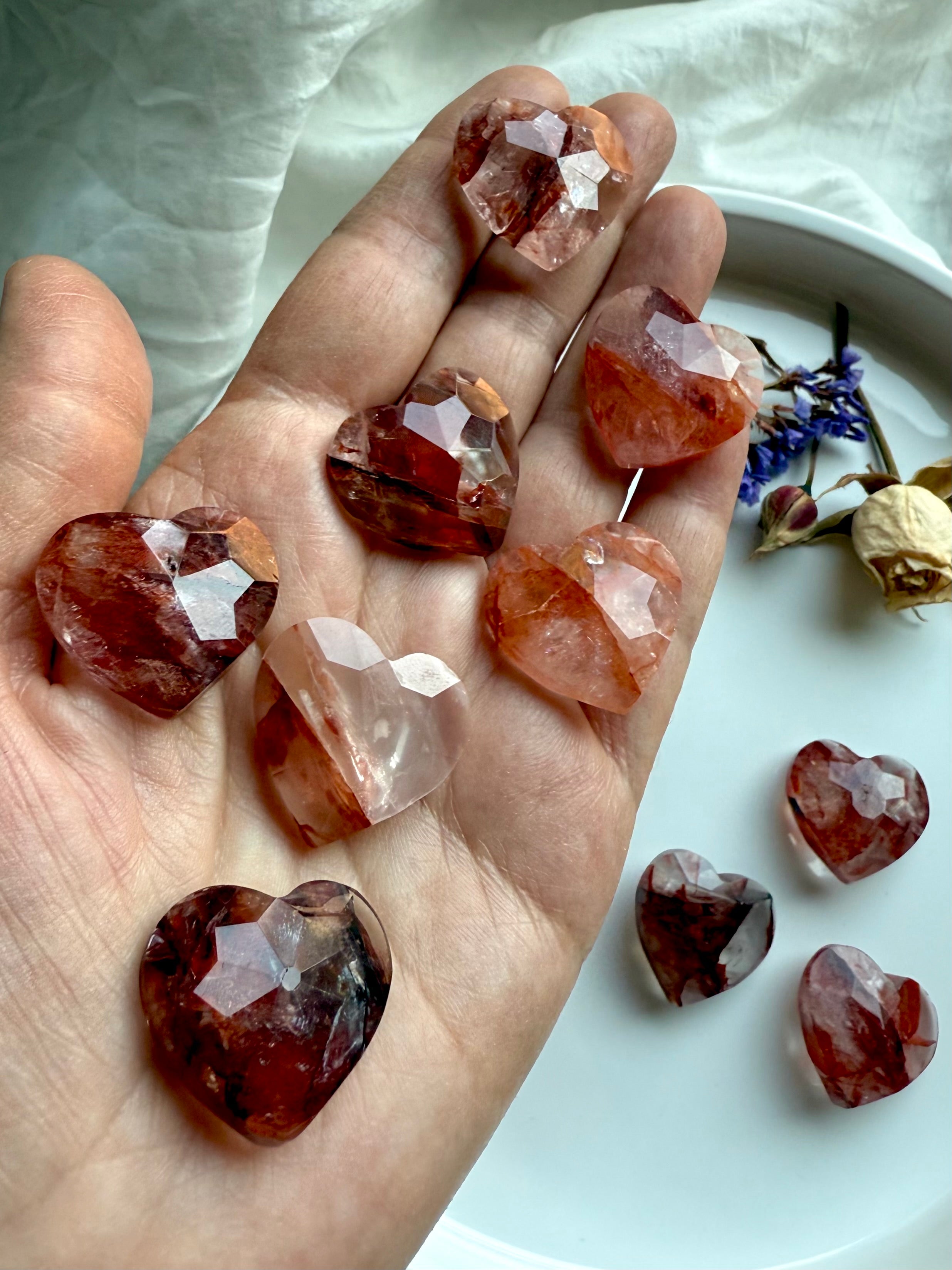 Array of faceted Fire Quartz mini crystal hearts displayed on hand – natural healing stones for grounding, balance, and spiritual support