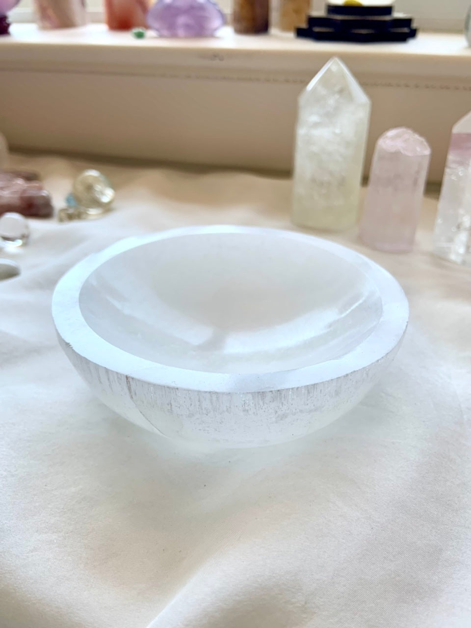 Wide angle of luminous Selenite charging bowl styled with crystals — altar décor for energy healing and Crown Chakra work