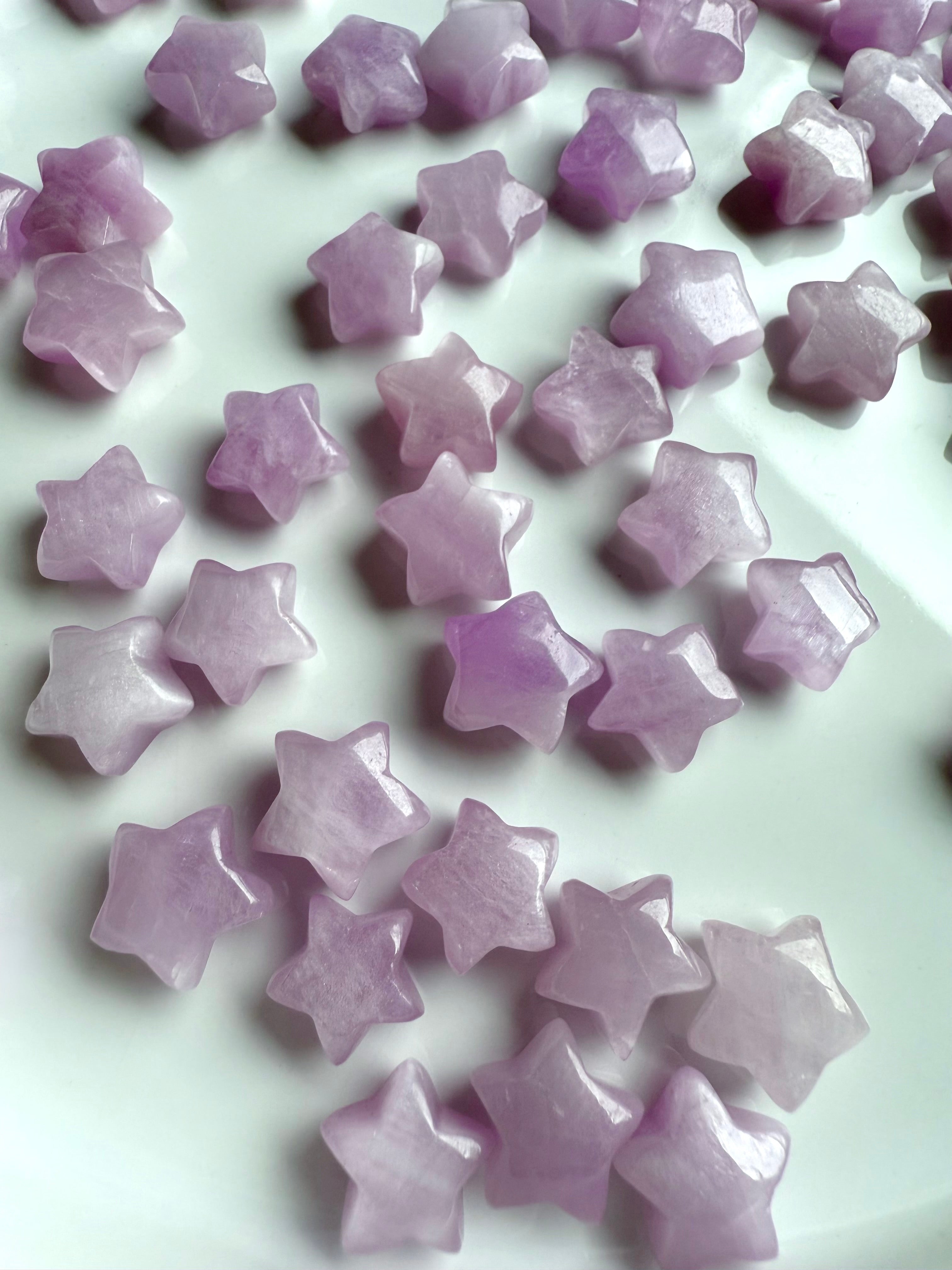 Kunzite mini star carvings on white background – tiny heart chakra crystals in pale pink and lilac hues with glossy polish and soft shimmer.