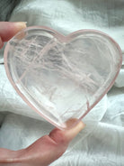 Rose Quartz heart bowl held in hand, showing its translucent pink clarity and etched inner inclusions for heart-healing energy.