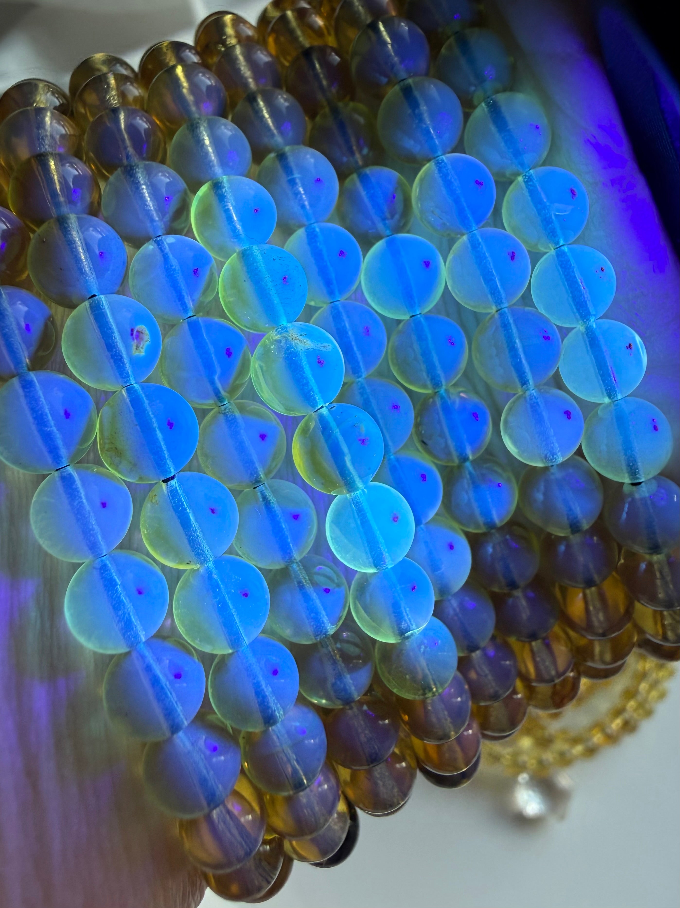 Close-up of Indonesian blue amber bracelet glowing bright blue under UV light showing natural UV reactive amber