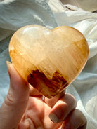 Golden Healer quartz heart palm stone in natural light highlighting iron rich patterns and glossy polish