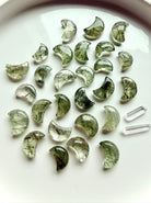 Green Tourmaline in Quartz moons on a white plate, green crystal carvings for Heart Chakra energy and abundance