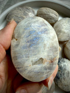 polished belomorite moonstone palm stone with blue flash and silvery gray feldspar patterns
