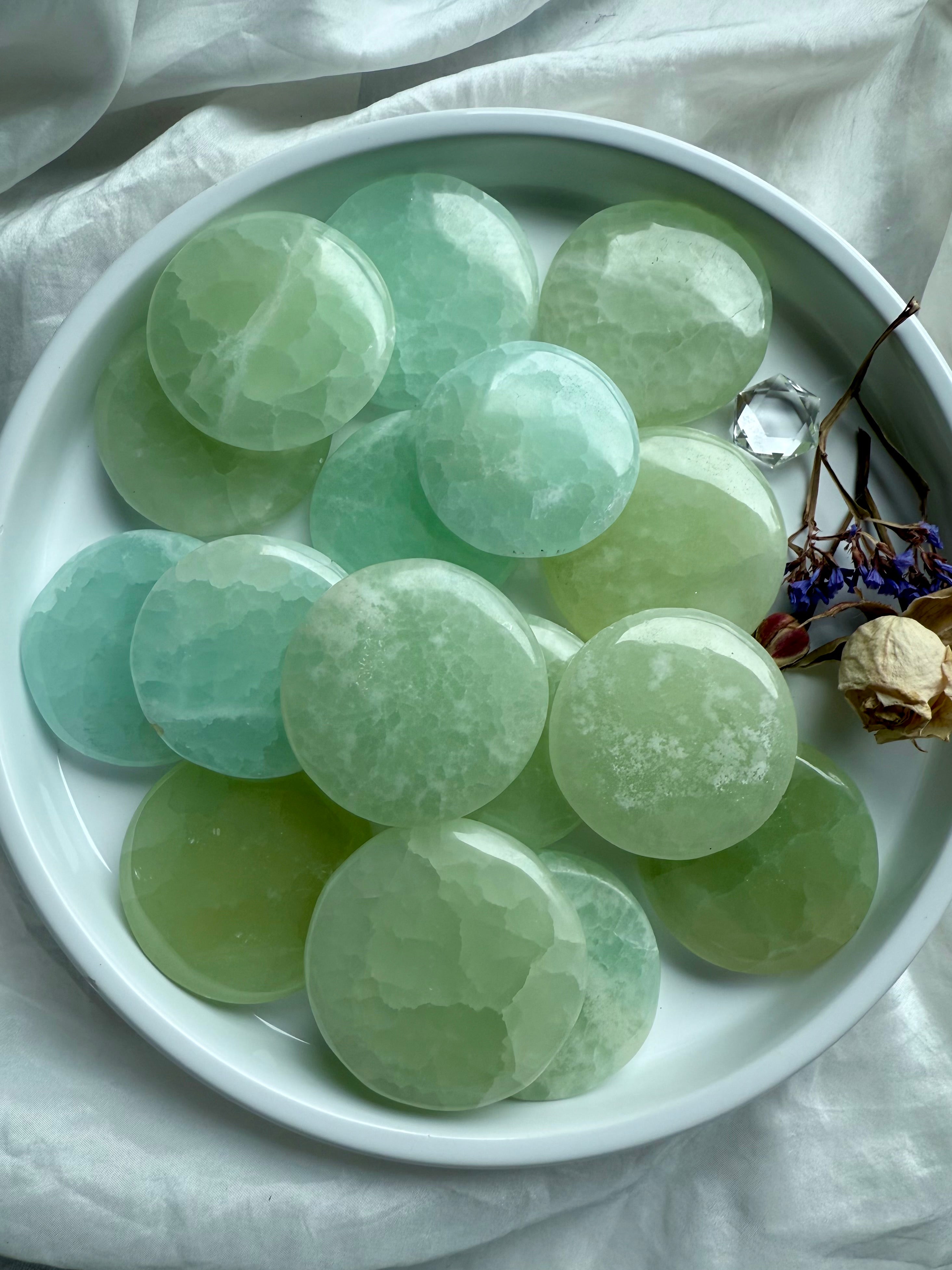 Soothing seafoam and sage green Pistachio Calcite stones in a white ceramic dish with dried botanicals for calm + clarity