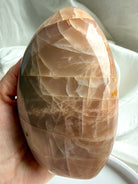 Peach Moonstone freeform crystal with luminous flash and polished surface shown in natural sunlight