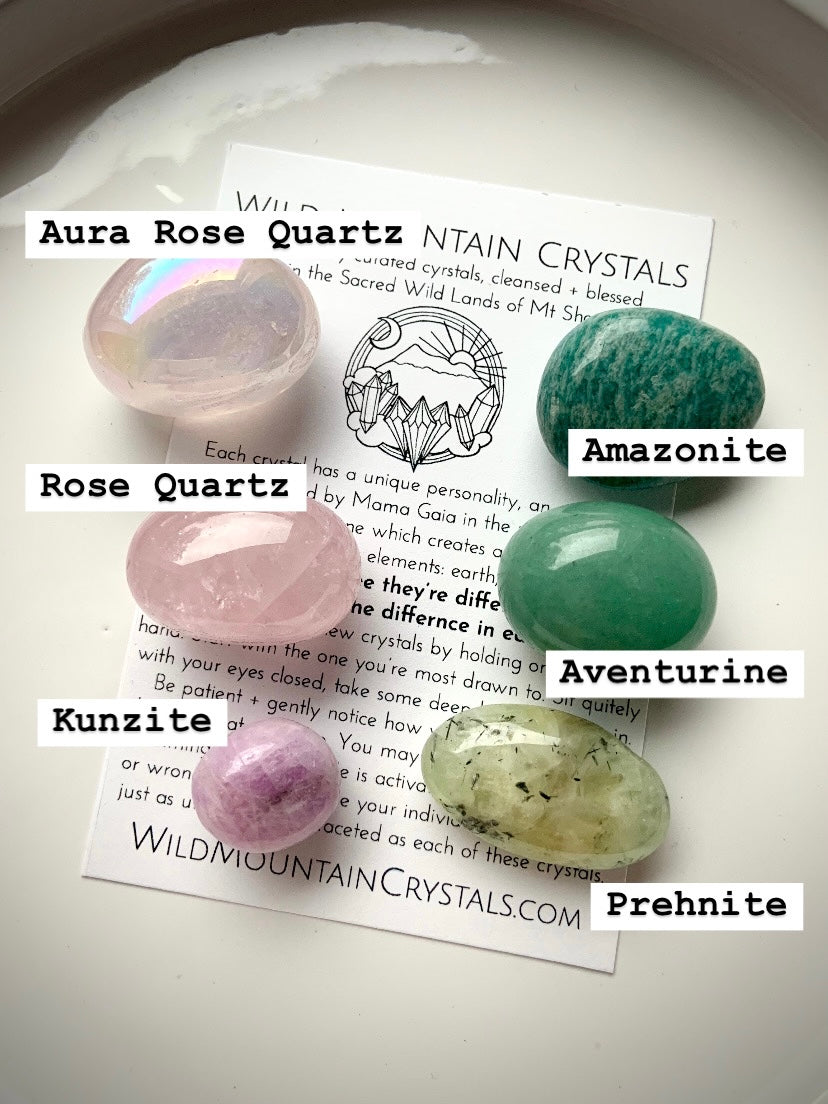 Heart Chakra crystal set labeled with stone names — aura rose quartz, rose quartz, kunzite, amazonite, prehnite, and green aventurine on branded Wild Mountain Crystals info card.