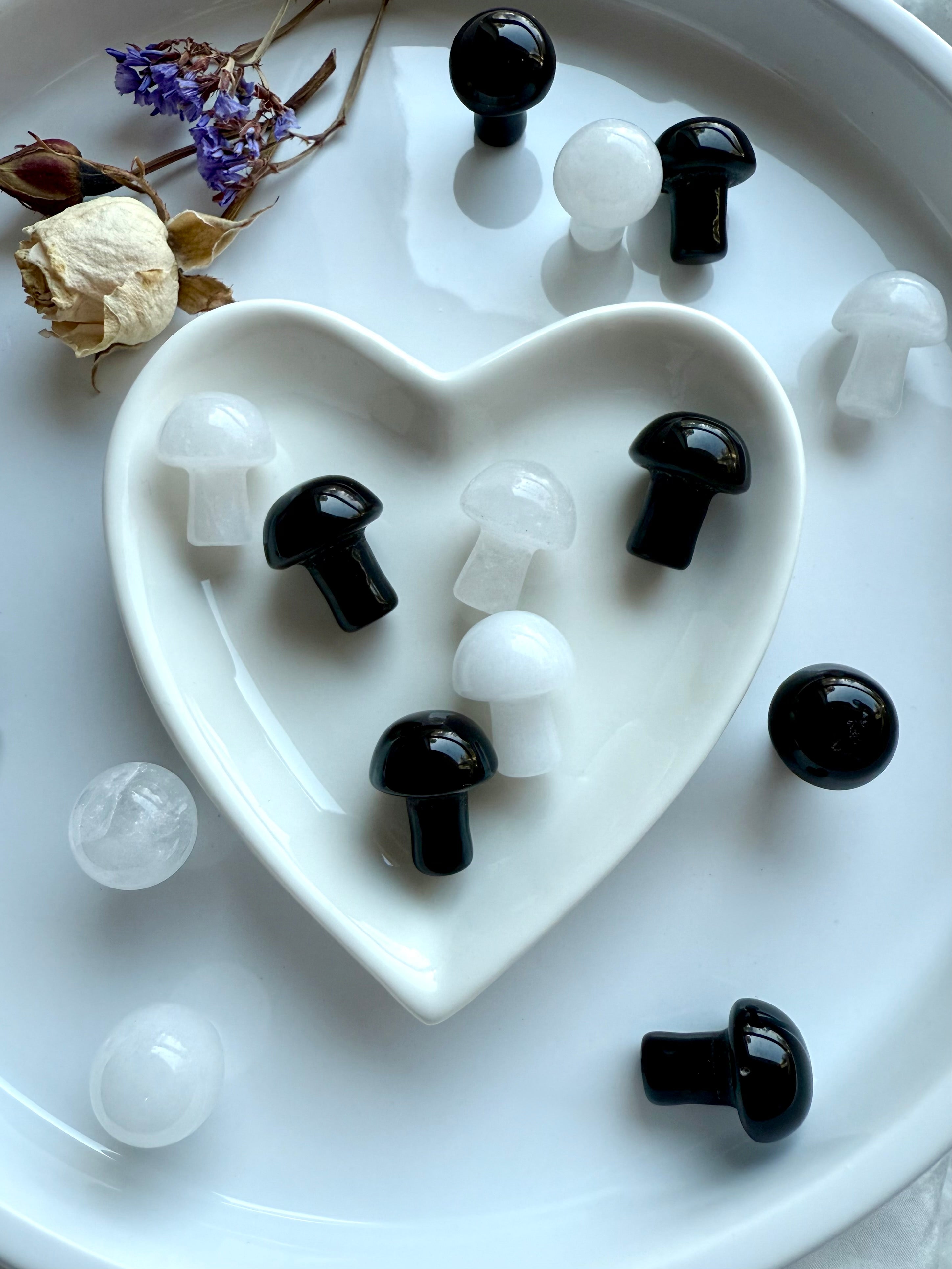 Black and white crystal mushrooms arranged in heart-shaped dish – symbolic mushrooms for transformation, protection, and crown chakra healing