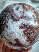 Red and white Crazy Lace Agate sphere with layered patterning and joyful root chakra vibrations