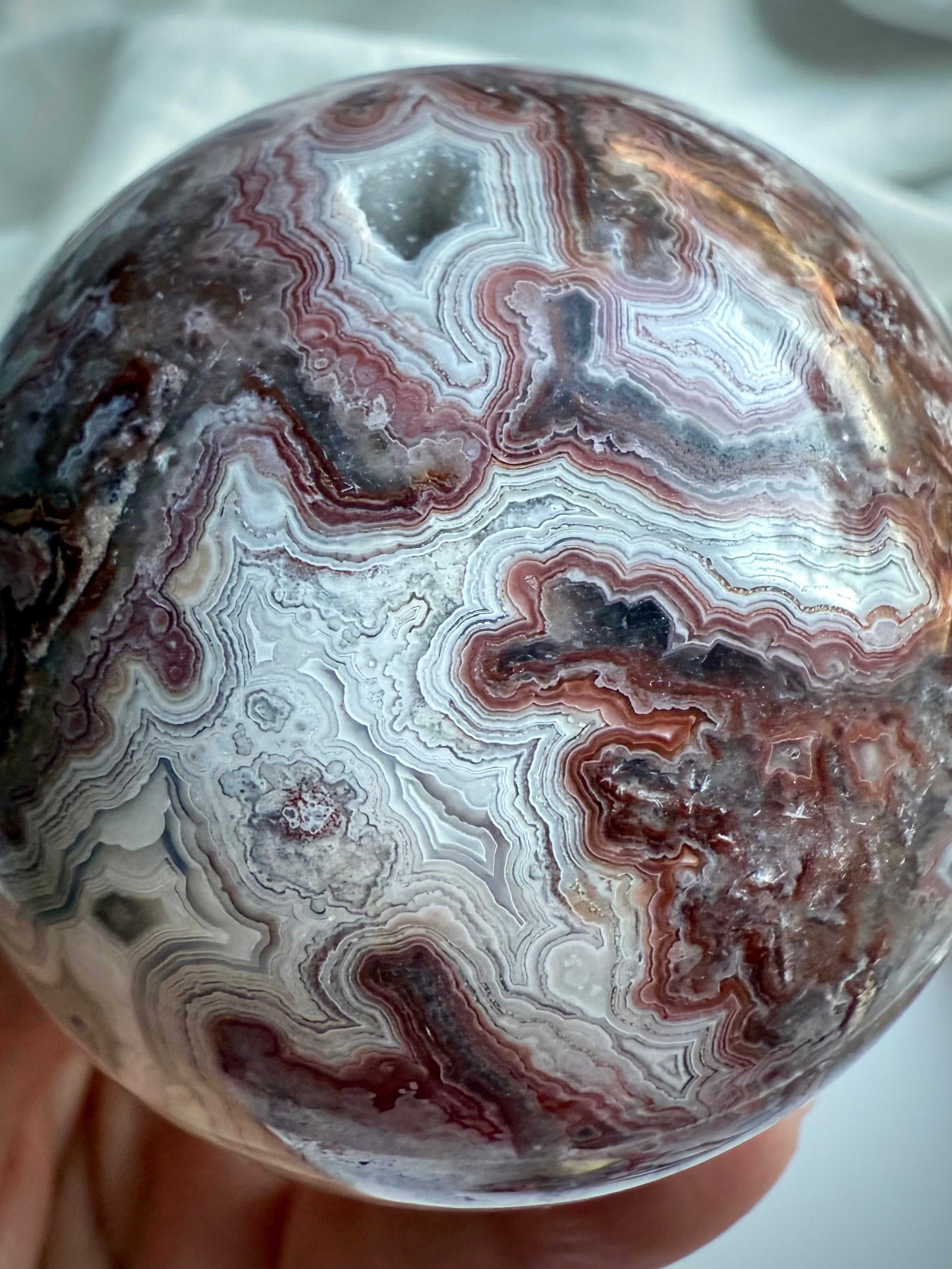 Red and white Crazy Lace Agate sphere with layered patterning and joyful root chakra vibrations