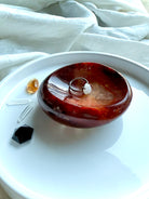 Carnelian crystal bowl styled with moonstone ring, citrine, clear quartz, and obsidian – sacred jewelry dish for ritual use