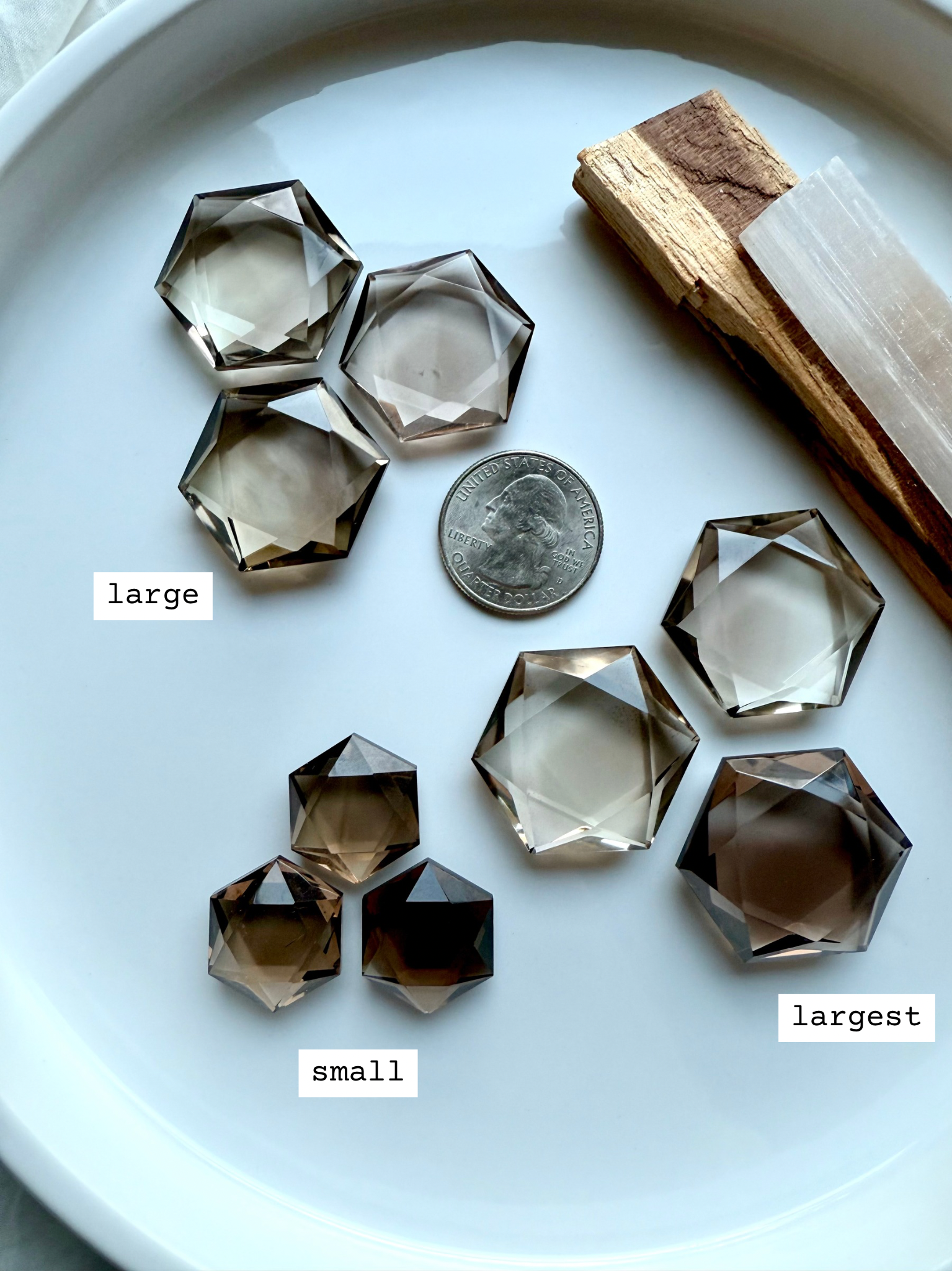 Overhead of Natural Smoky Quartz hexagon crystals carvings in three sizes marked for reference and shown with a US quarter for scale 