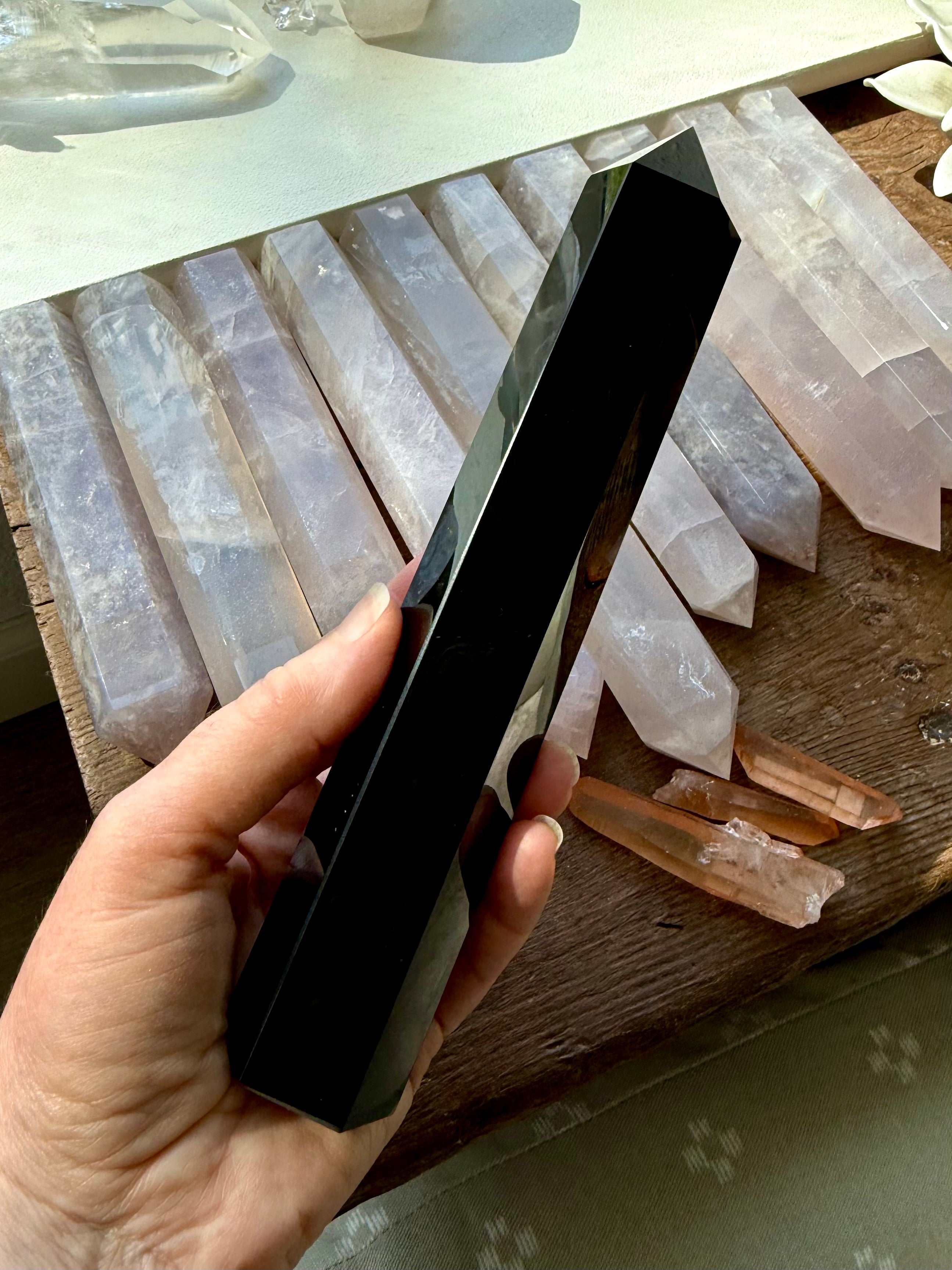 Large Black Obsidian tower angled over a row of rose quartz points — grounding stone for crystal grids & altar décor.