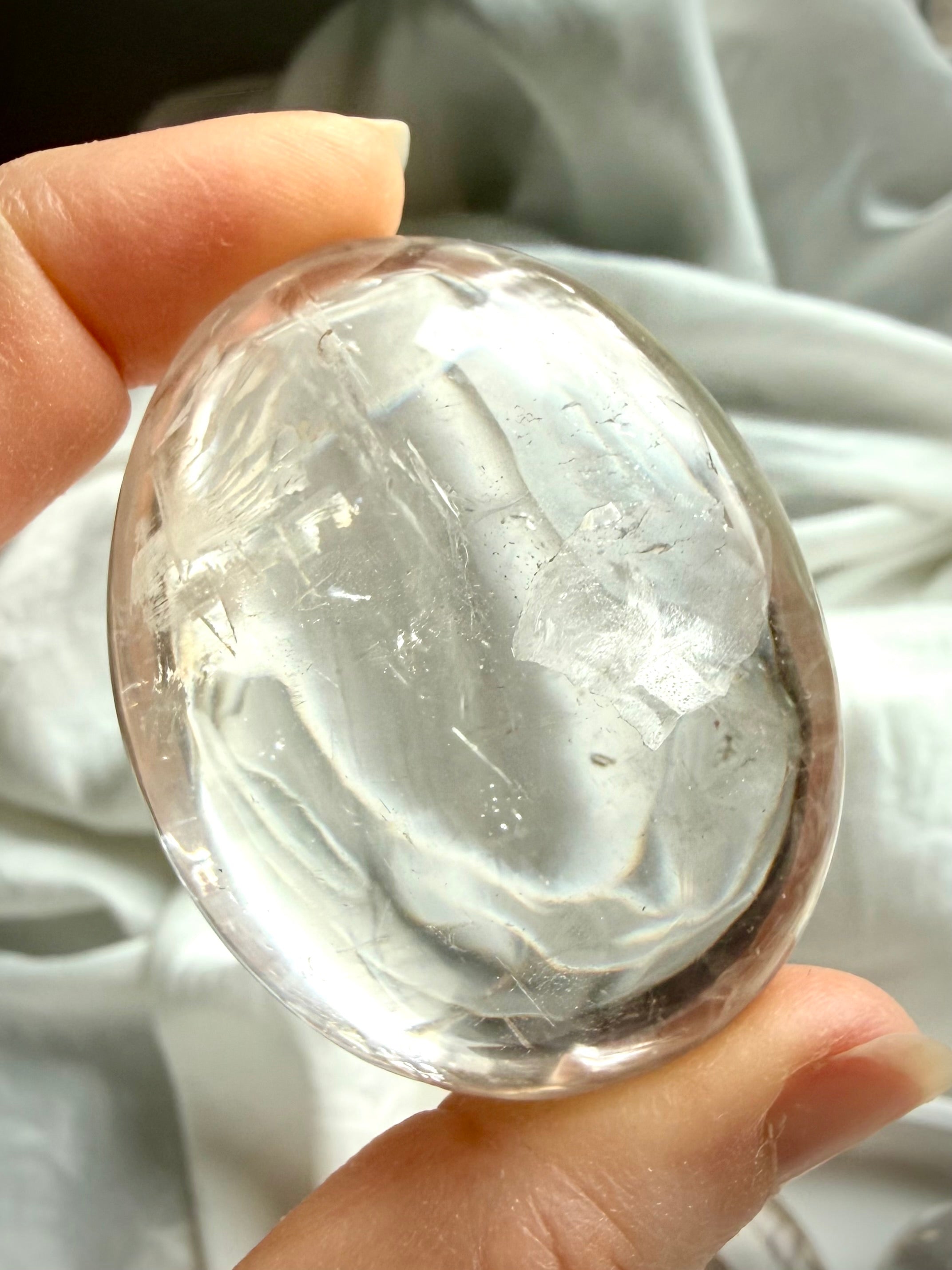Detailed image of a clear quartz palm stone with subtle inclusions and internal structure