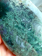 Close-up of Moss Agate flame with mossy green chlorite patterns and soft sage tones, high-gloss polished crystal