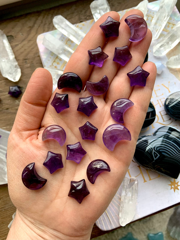 Mini sized purple amethyst moons and stars shown on my hand with some other pretty crystals in the background