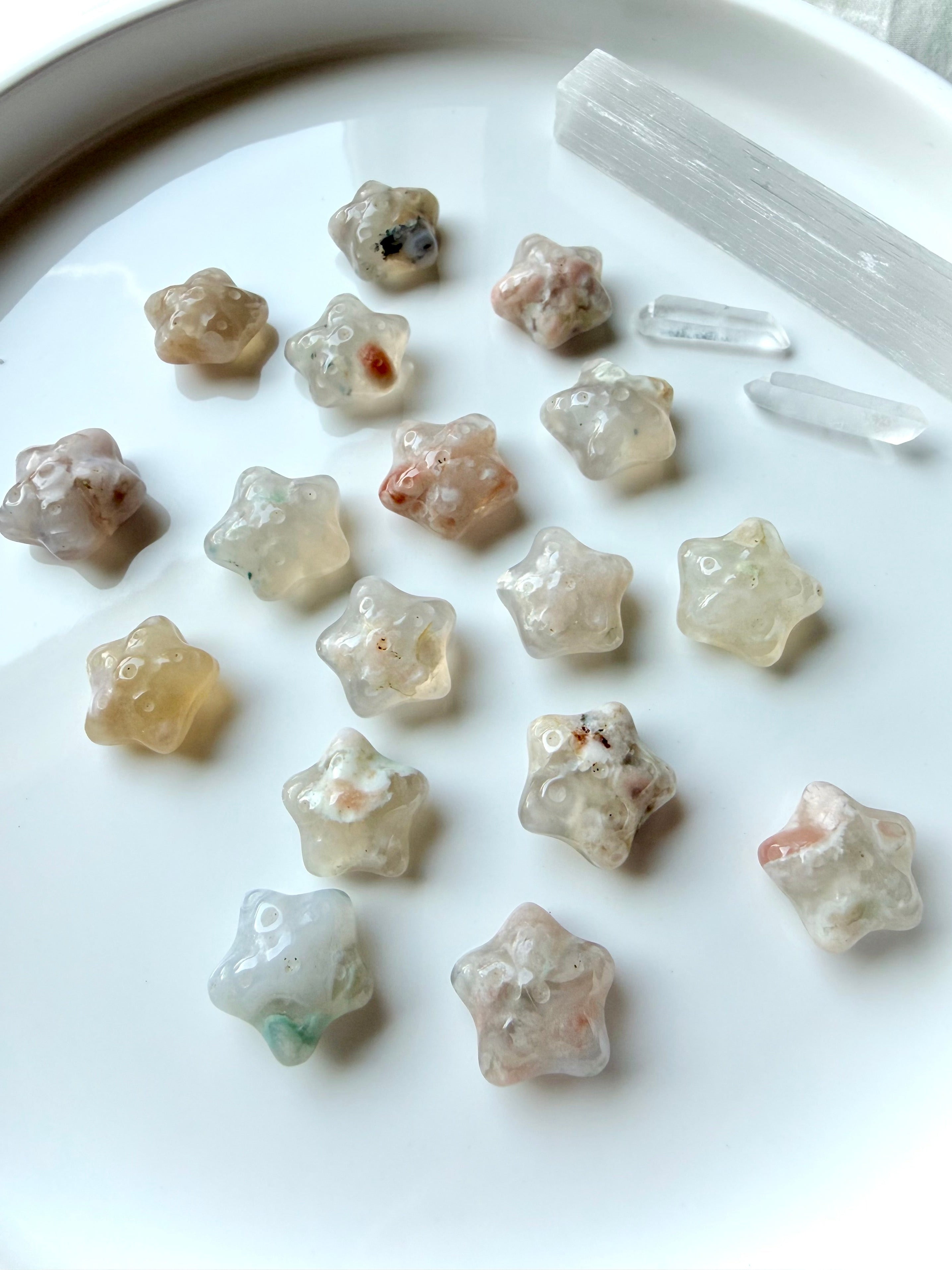 assorted mini Flower Agate starfish carvings arranged on plate with natural floral inclusions and ocean-inspired shape
