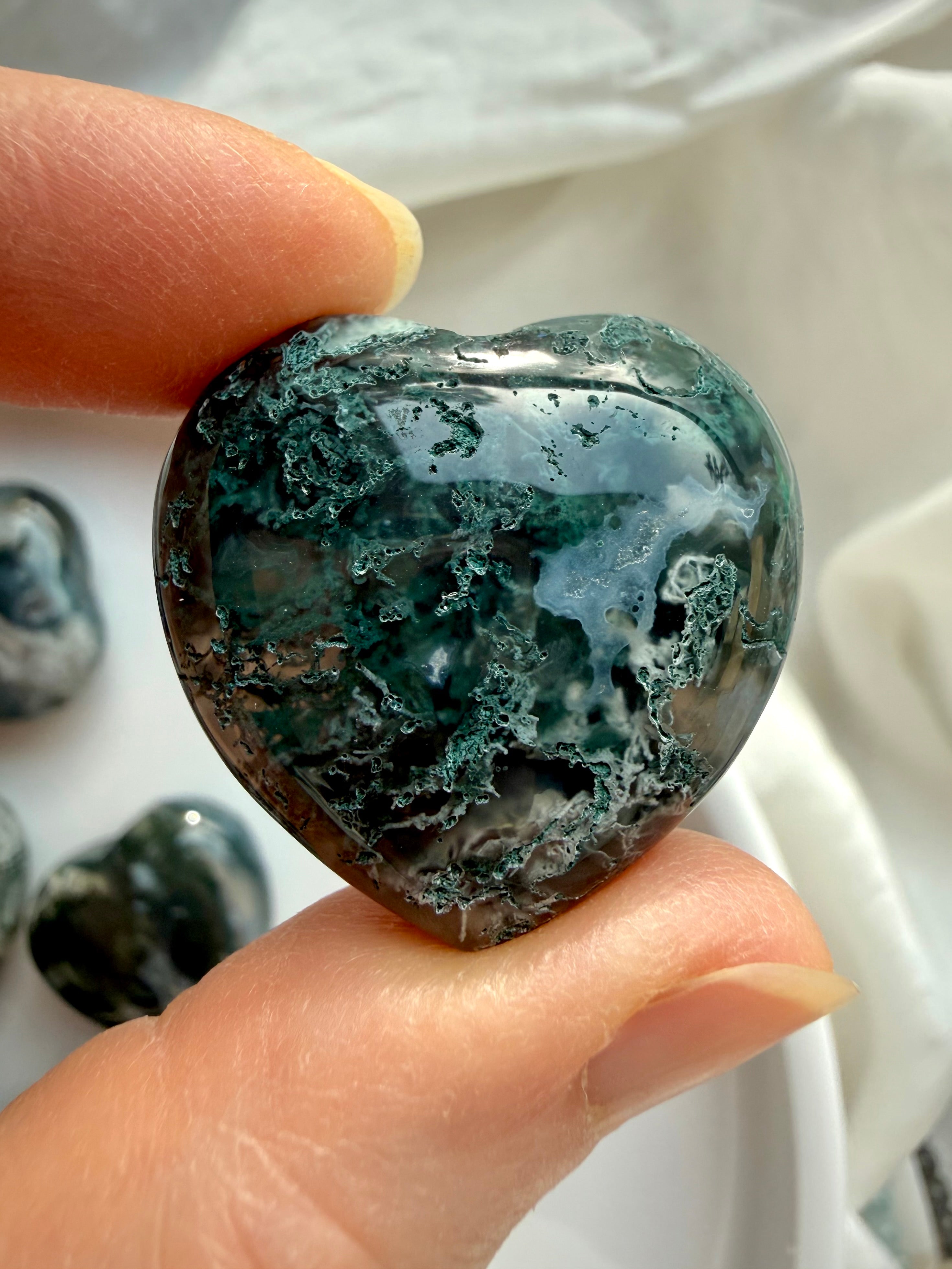 Close-up of a Moss Agate heart showing rich forest-green moss inclusions and organic stone texture