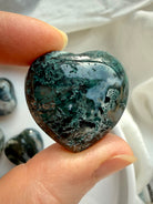 Close-up of a Moss Agate heart showing rich forest-green moss inclusions and organic stone texture