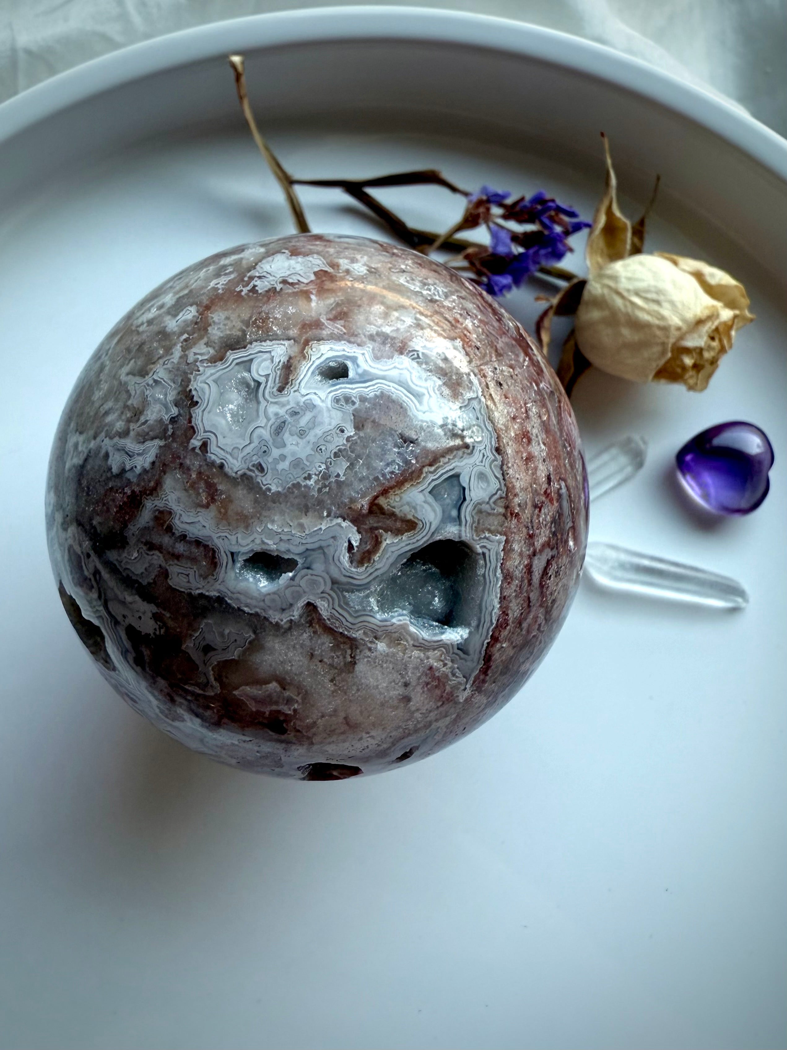 Crystal sphere of Crazy Lace Agate viewed from above with striking red bands and grounding metaphysical properties