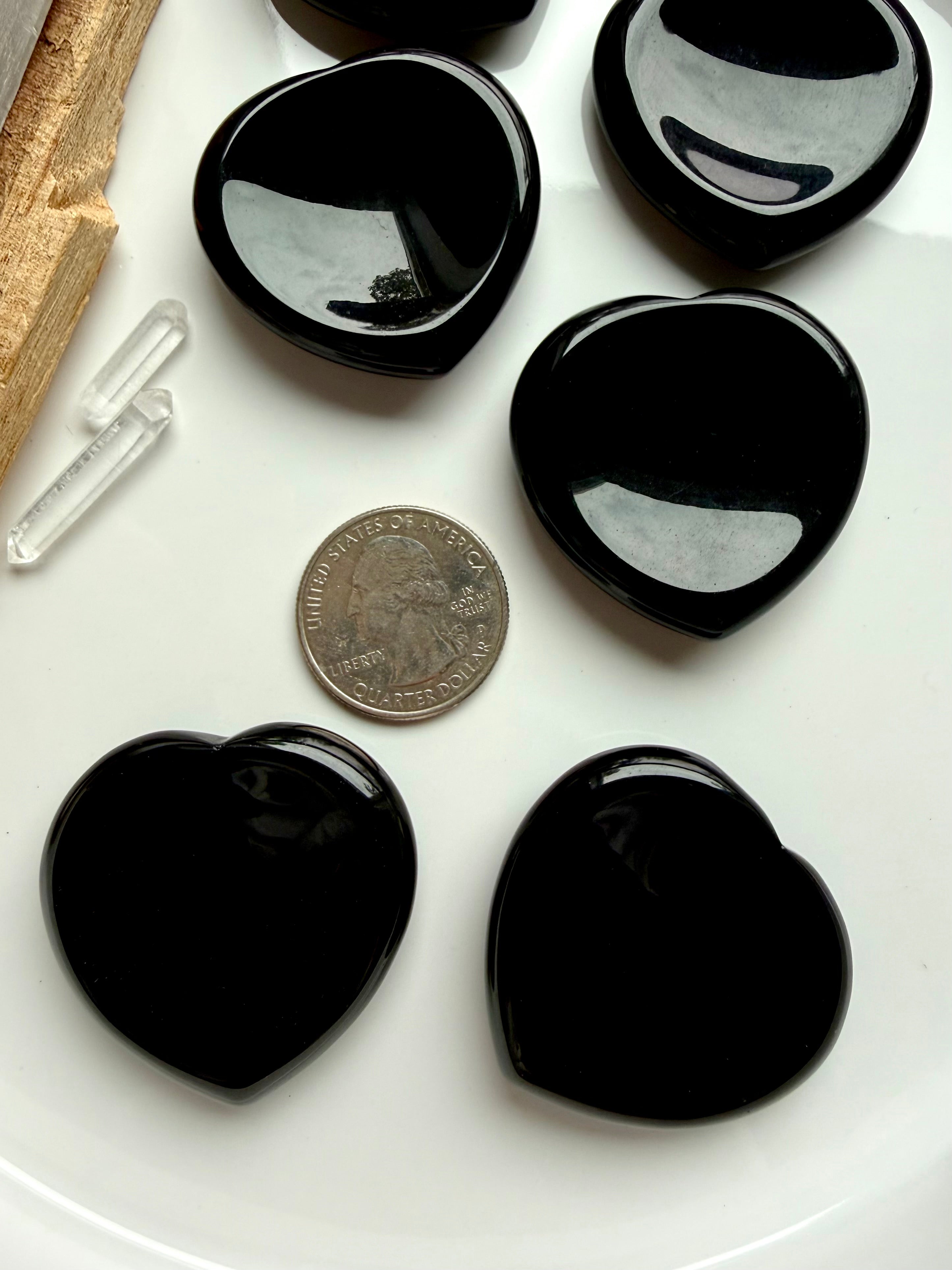 Black obsidian heart worry stones shown with quarter for size scale