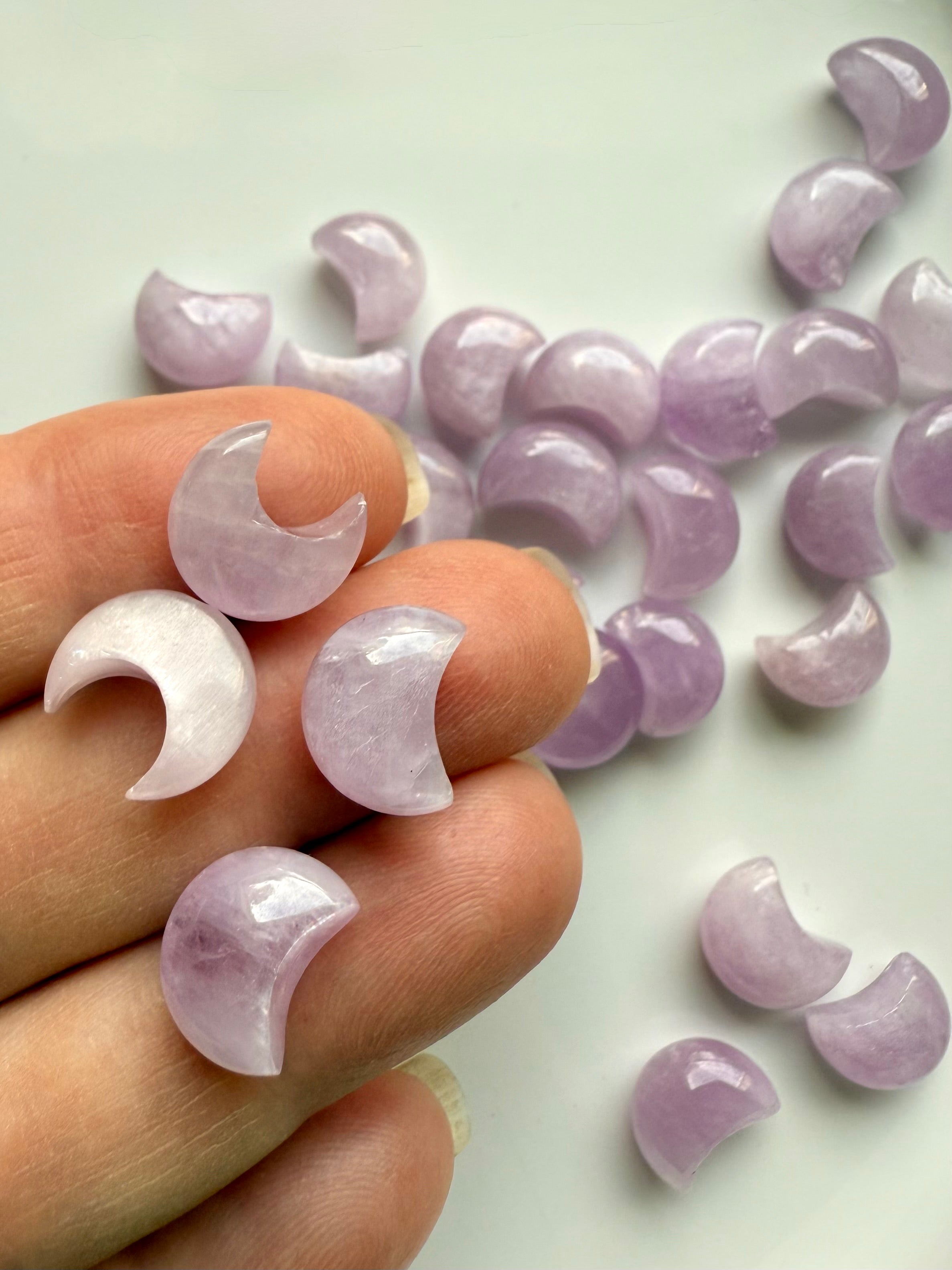 Closeup of mini Pink Kunzite moon carvings on fingertips — heart chakra crystals for love, compassion & peace.