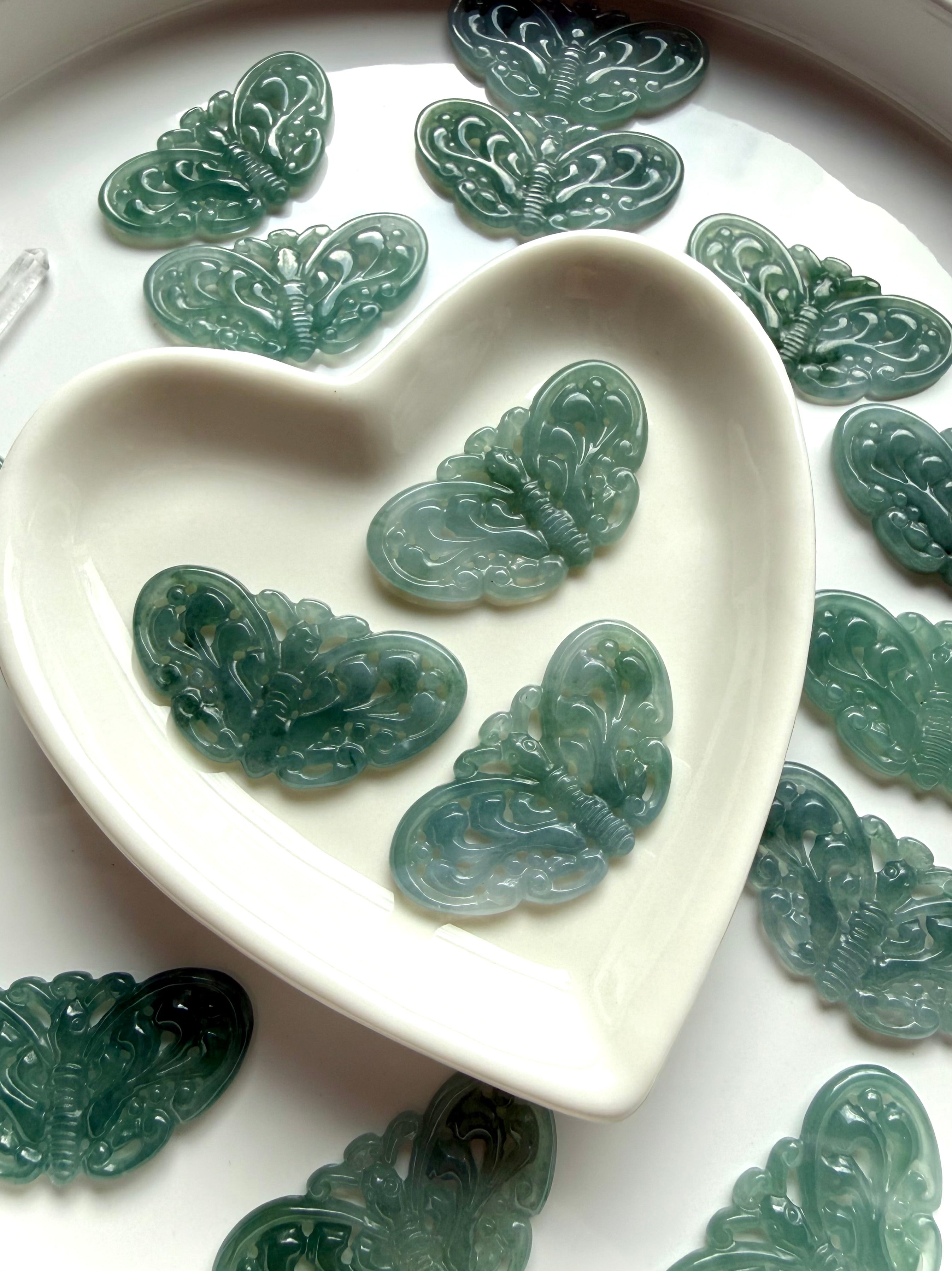 Blue Water Jade butterfly carvings displayed in white heart dish showing teal color variation and detailed carving