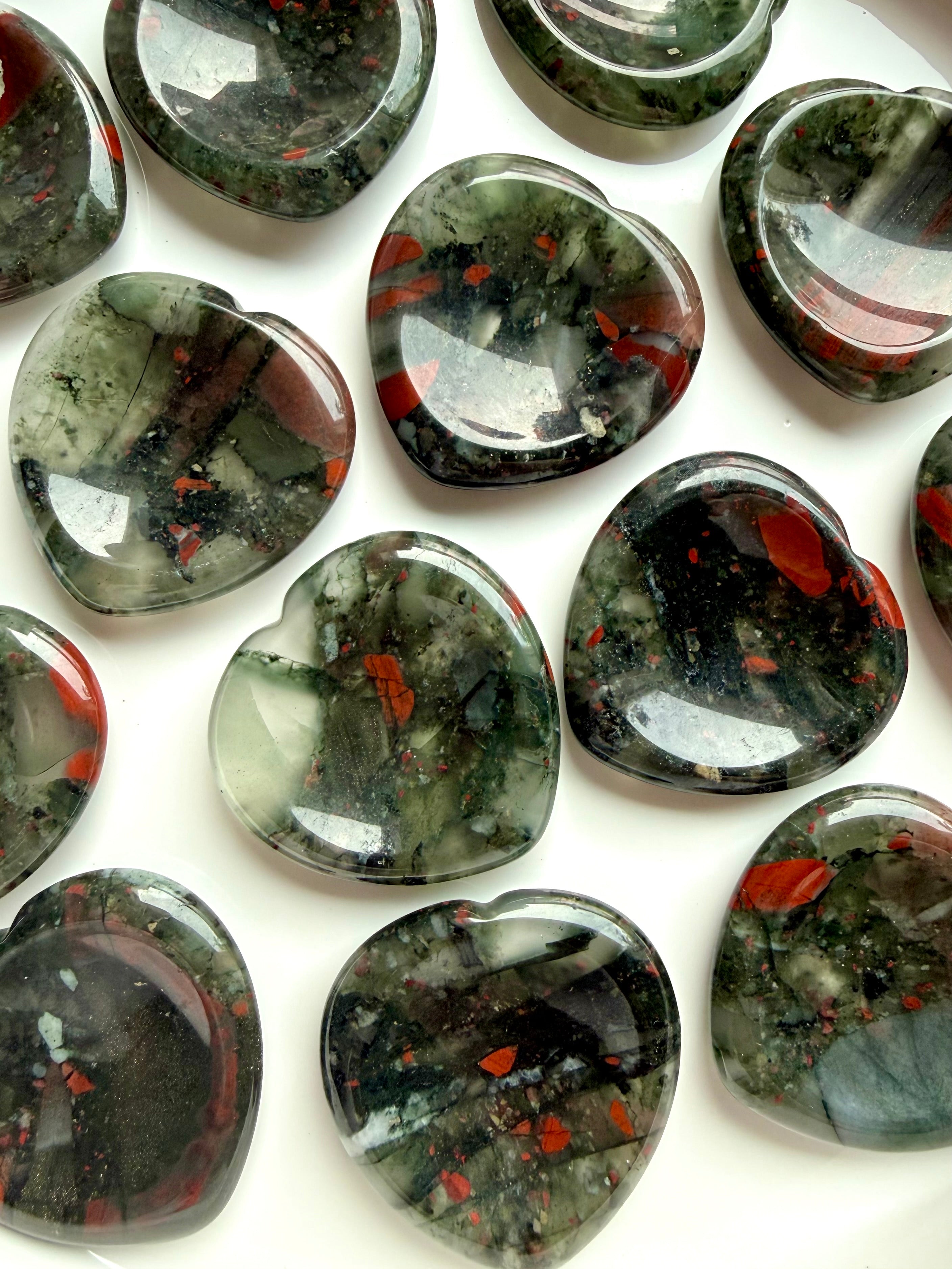 top view of bloodstone hearts in bowl with varied red and green patterning, worry stones for strength grounding and resilience