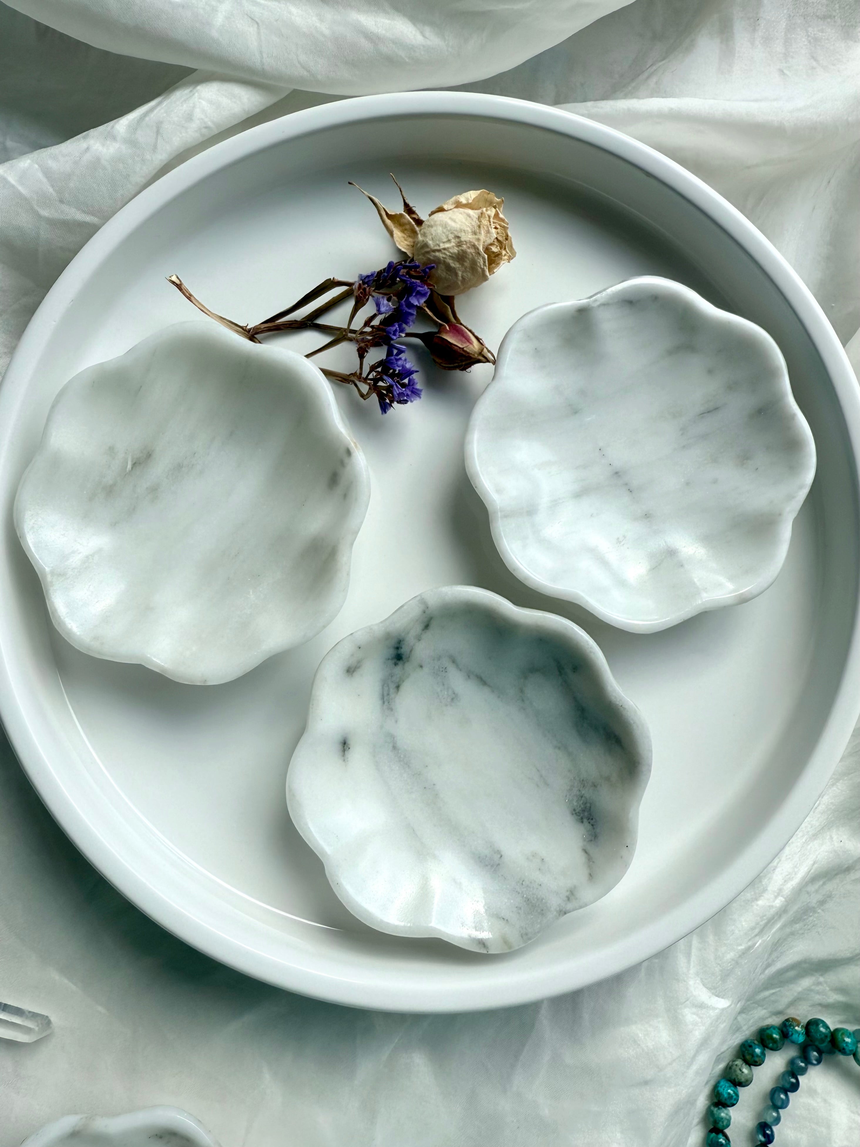 Set of three white marble daisy bowls with natural gray veining, styled with dried flowers on white tray