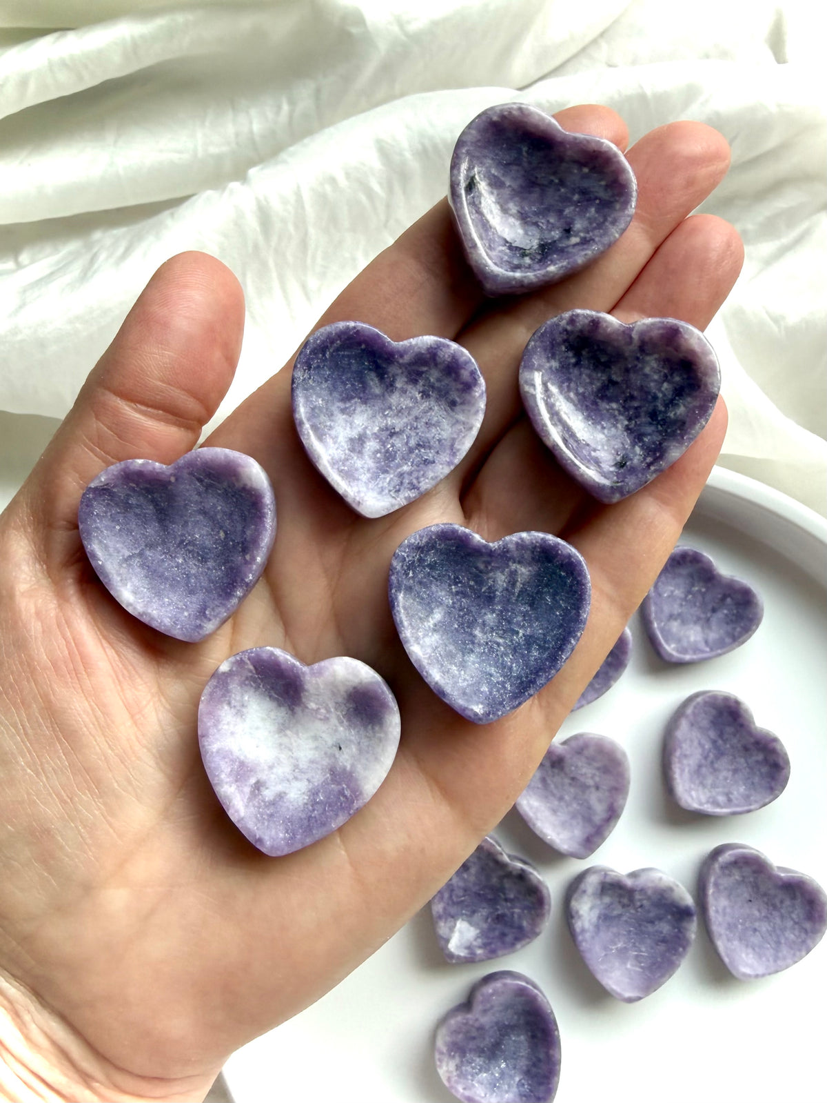 Purple Lepidolite heart bowls held in hand showing miniature size, lavender tones and natural color variation