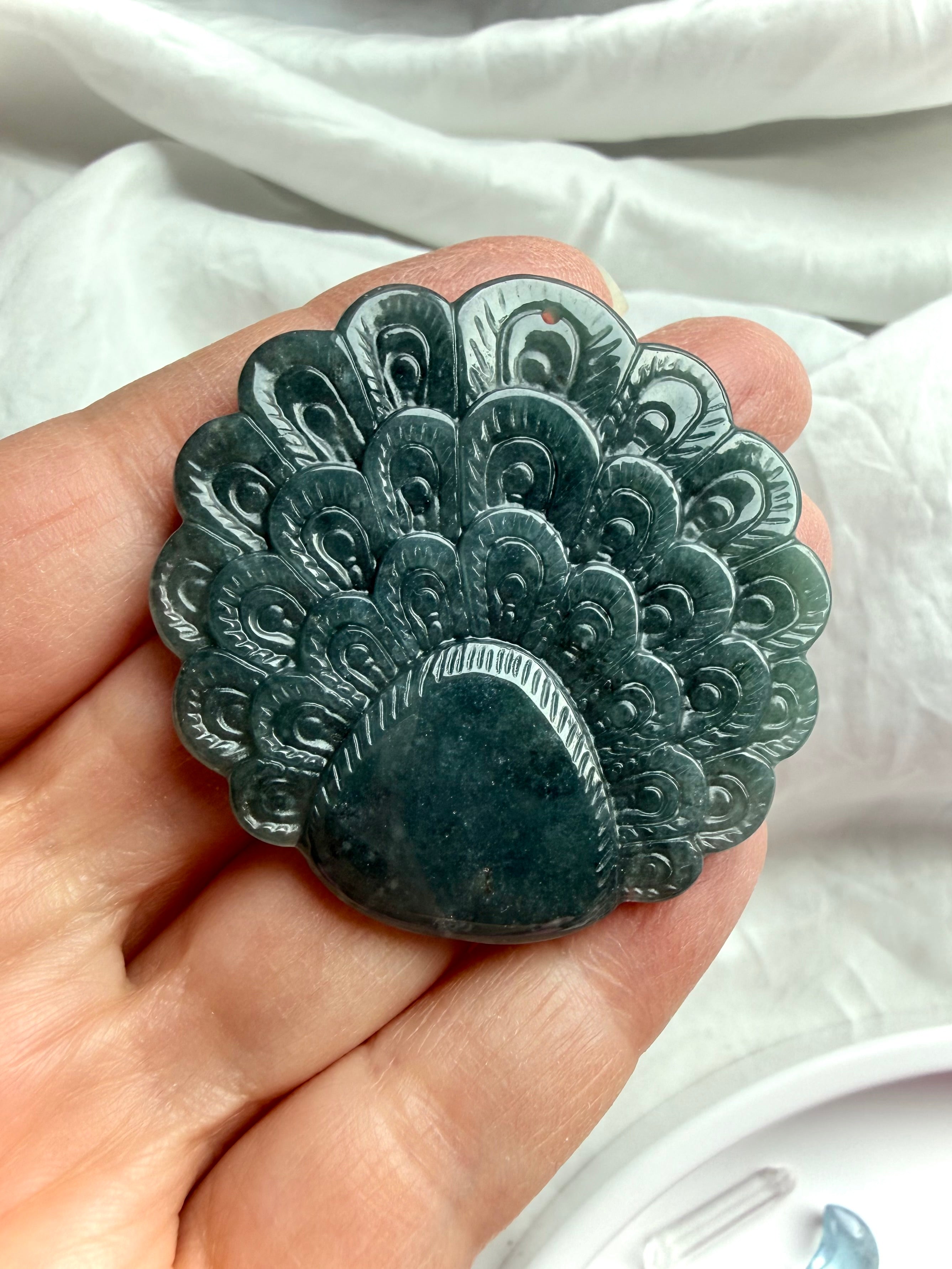 Back view of a Blue Water Jade peacock carving with detailed feather pattern and polished finish