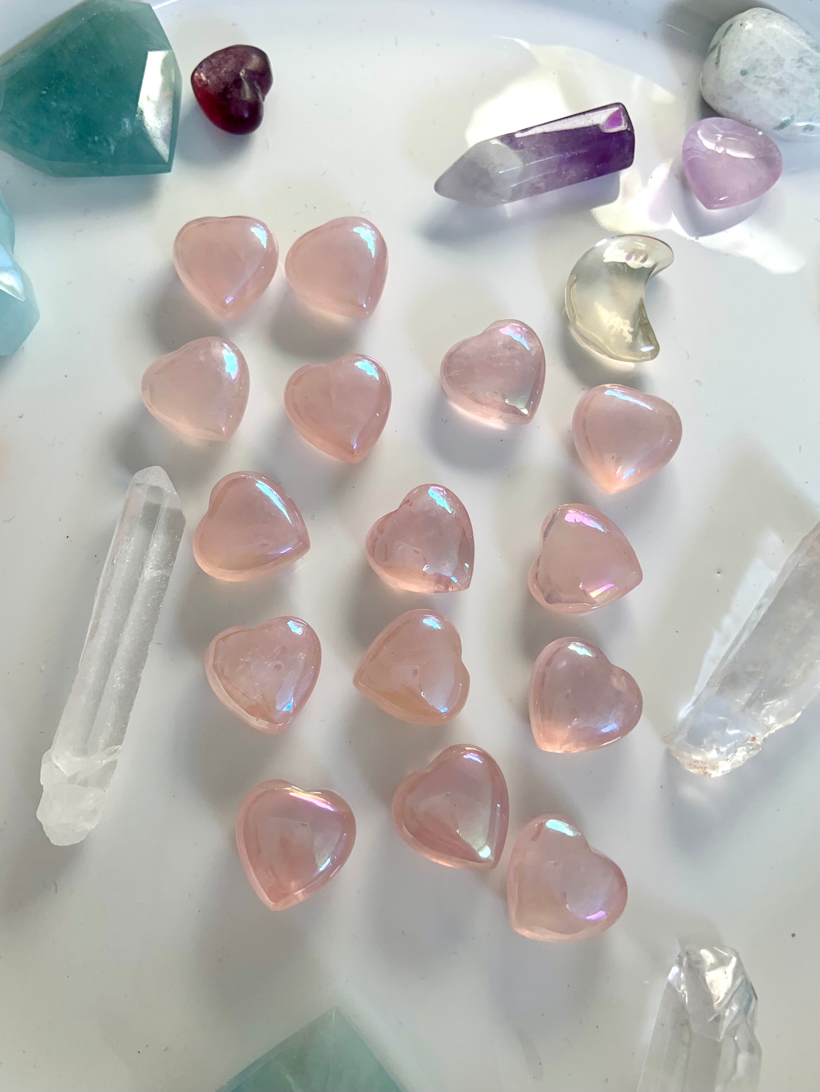 Angled view of aura rose quartz hearts with crystal points & celestial carvings — glowing pink stones for heart chakra healing & sacred decor