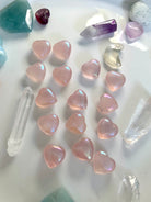 Angled view of aura rose quartz hearts with crystal points & celestial carvings — glowing pink stones for heart chakra healing & sacred decor