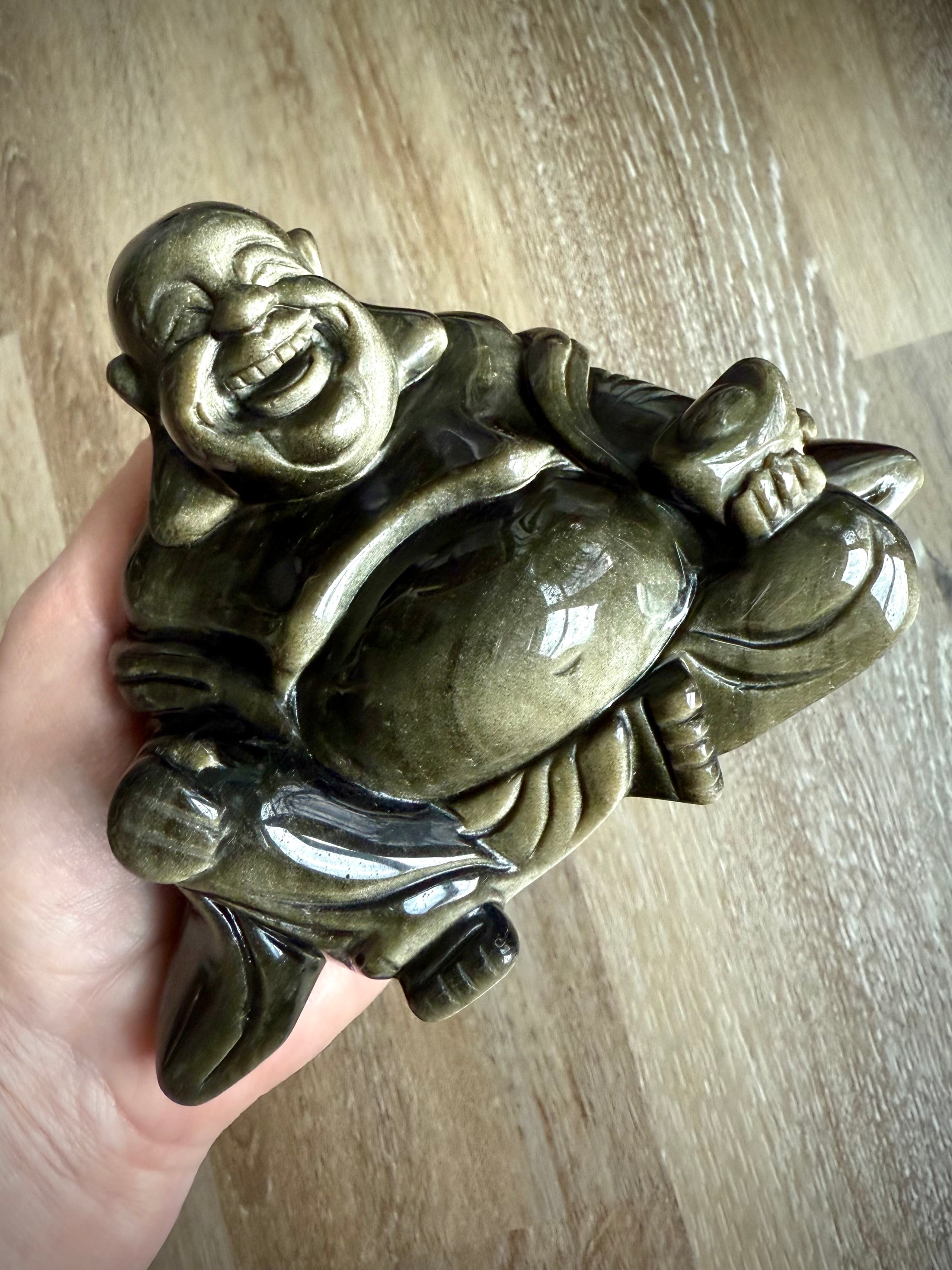 Golden Sheen Obsidian Laughing Buddha statue shown in hand – hand-carved crystal carving for joy, empowerment, and transformation