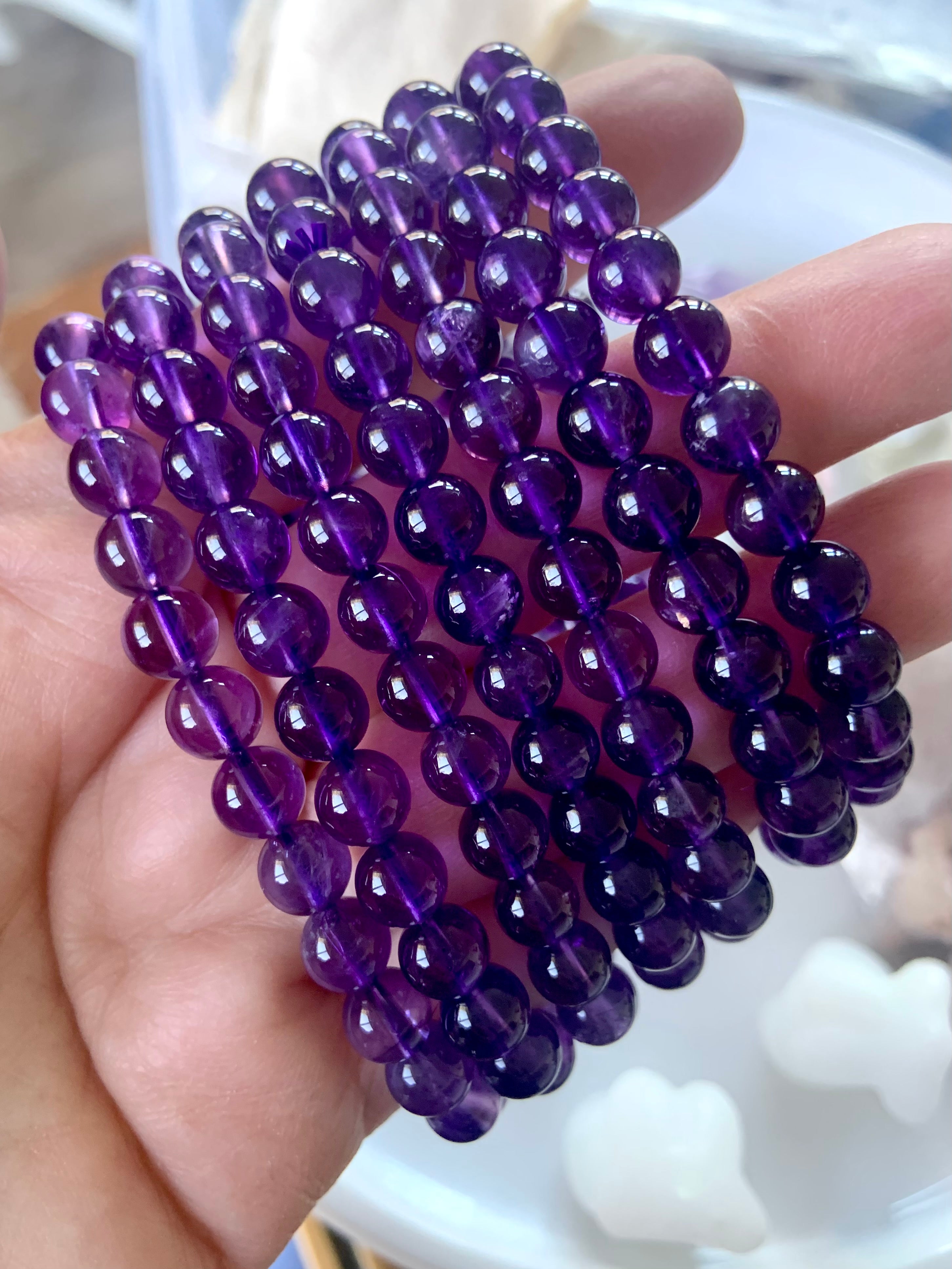 An array of high quality deep purple amethyst beaded bracelets shown on a hand 